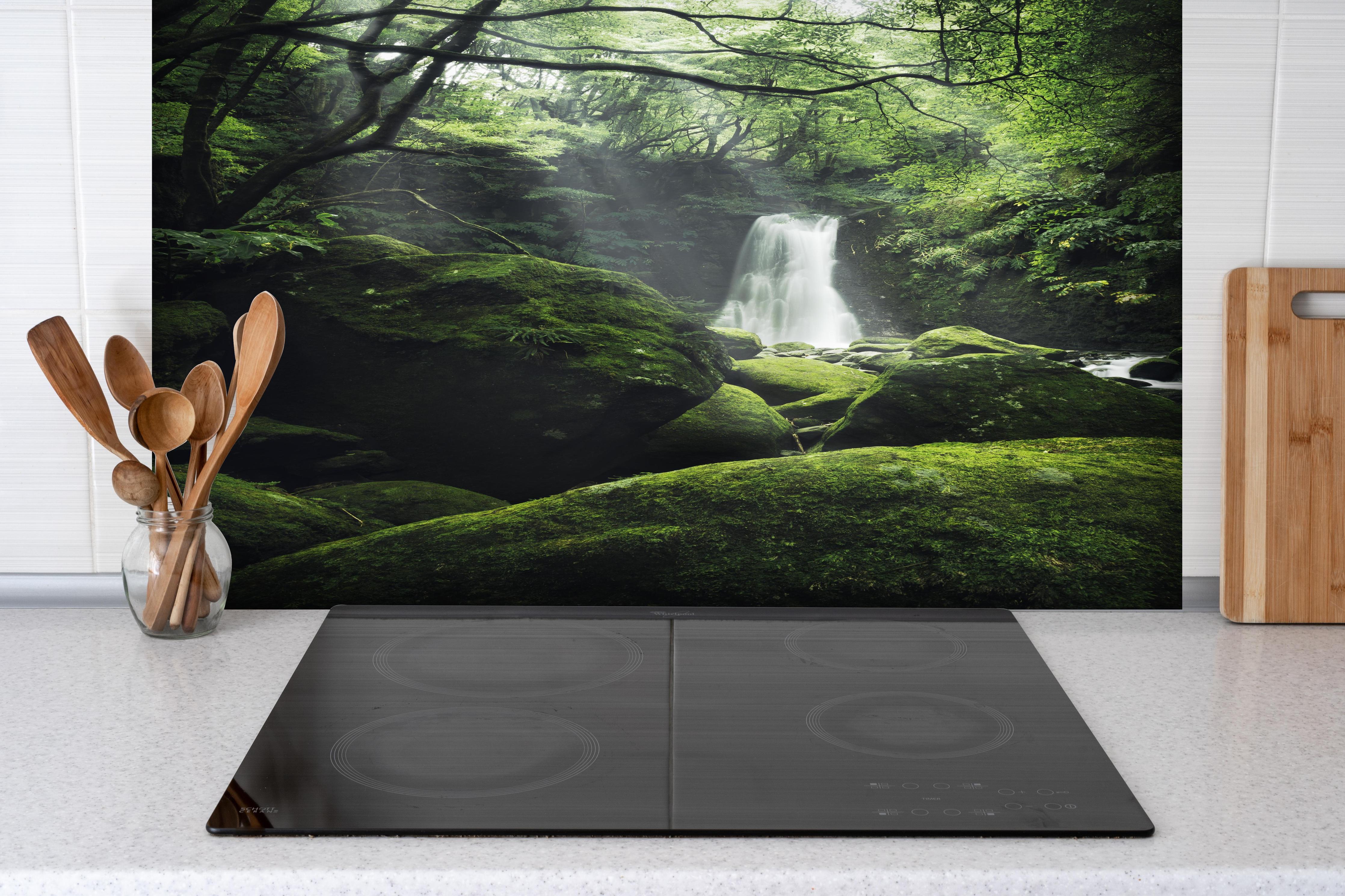 Spritzschutz - Verträumter Wasserfall im grünen Urwald hinter einem Cerankochfeld zwischen Holz-Kochutensilien