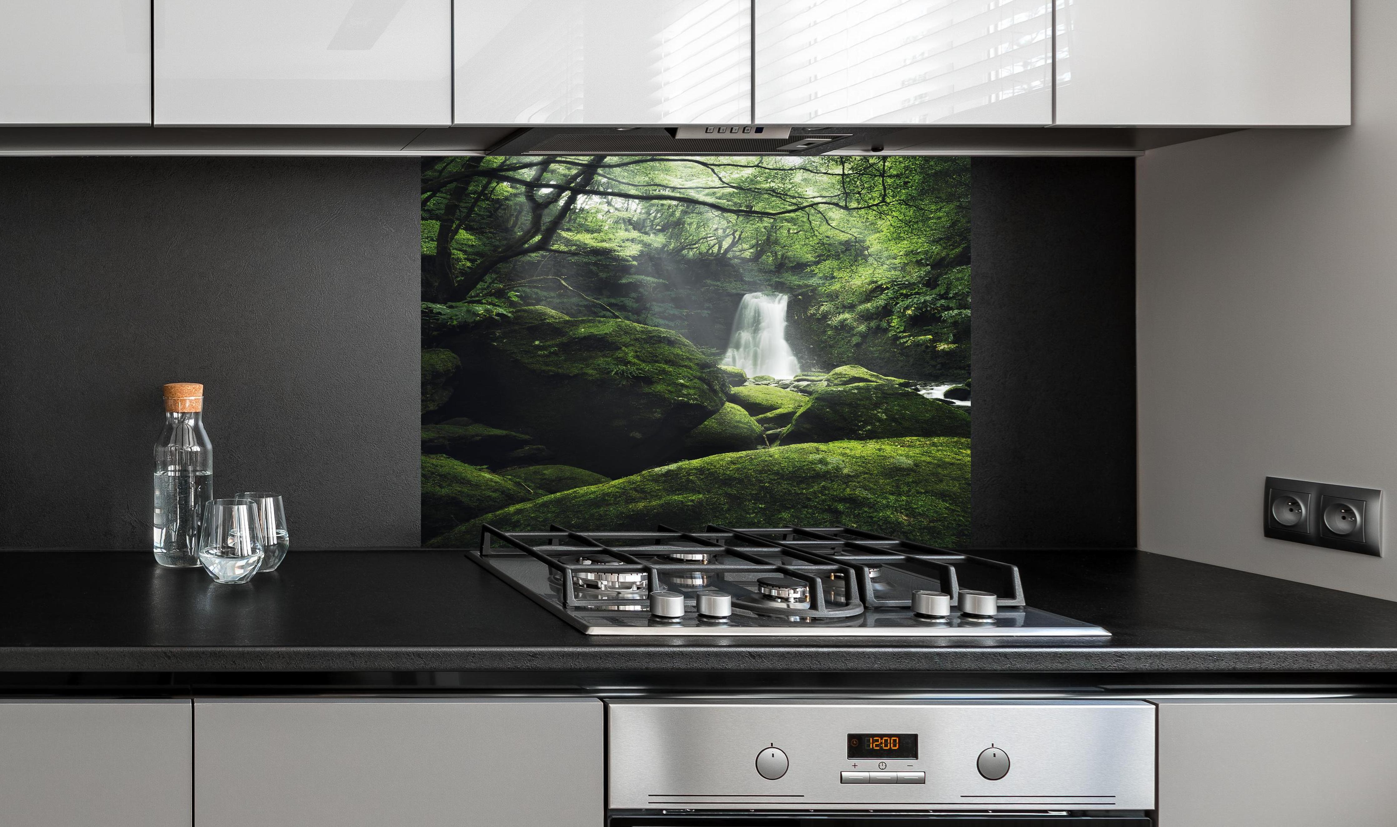 Spritzschutz - Verträumter Wasserfall im grünen Urwald hinter einem Cerankochfeld zwischen Holz-Kochutensilien