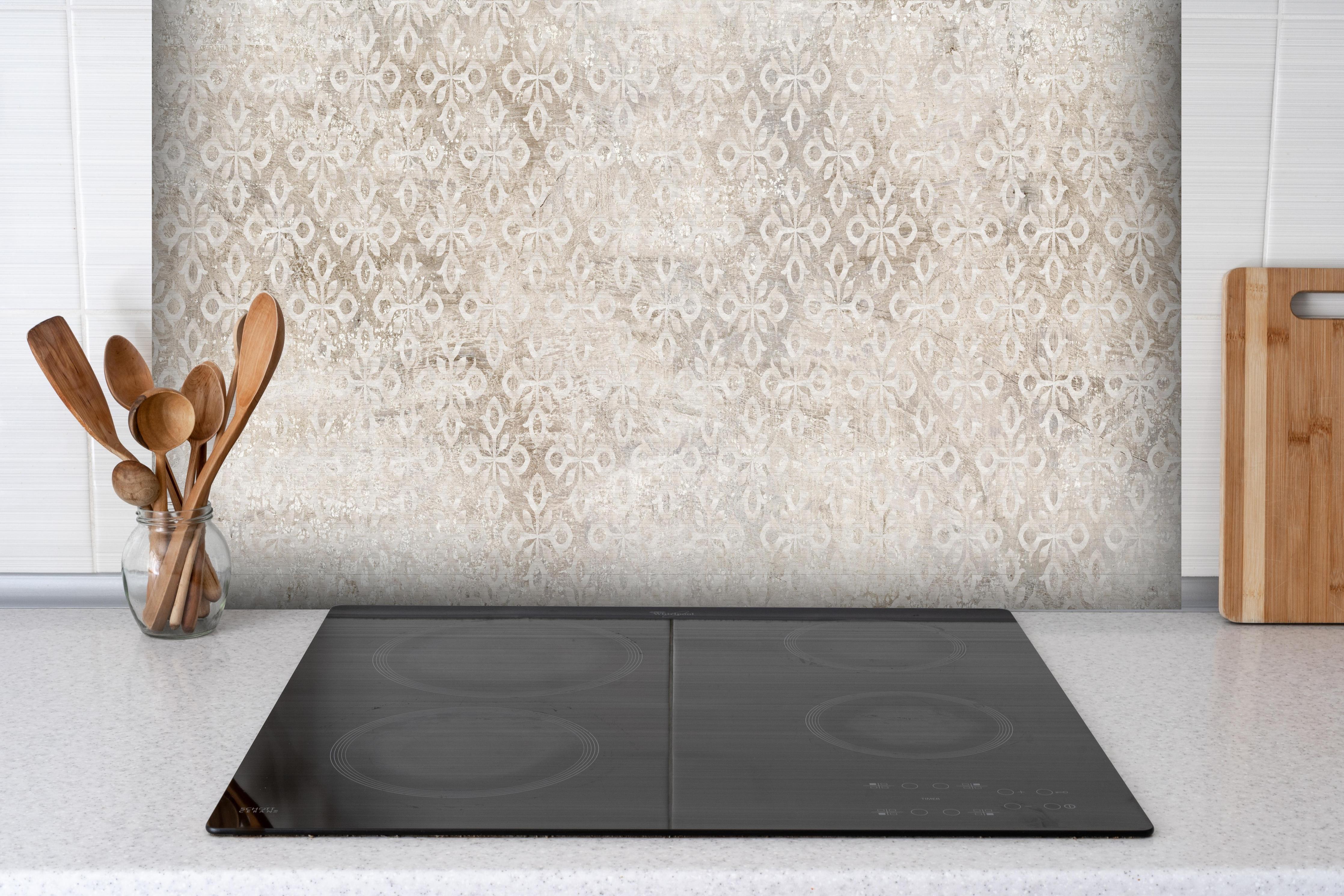 Spritzschutz - Verunreinigtes Ornament Muster hinter einem Cerankochfeld zwischen Holz-Kochutensilien