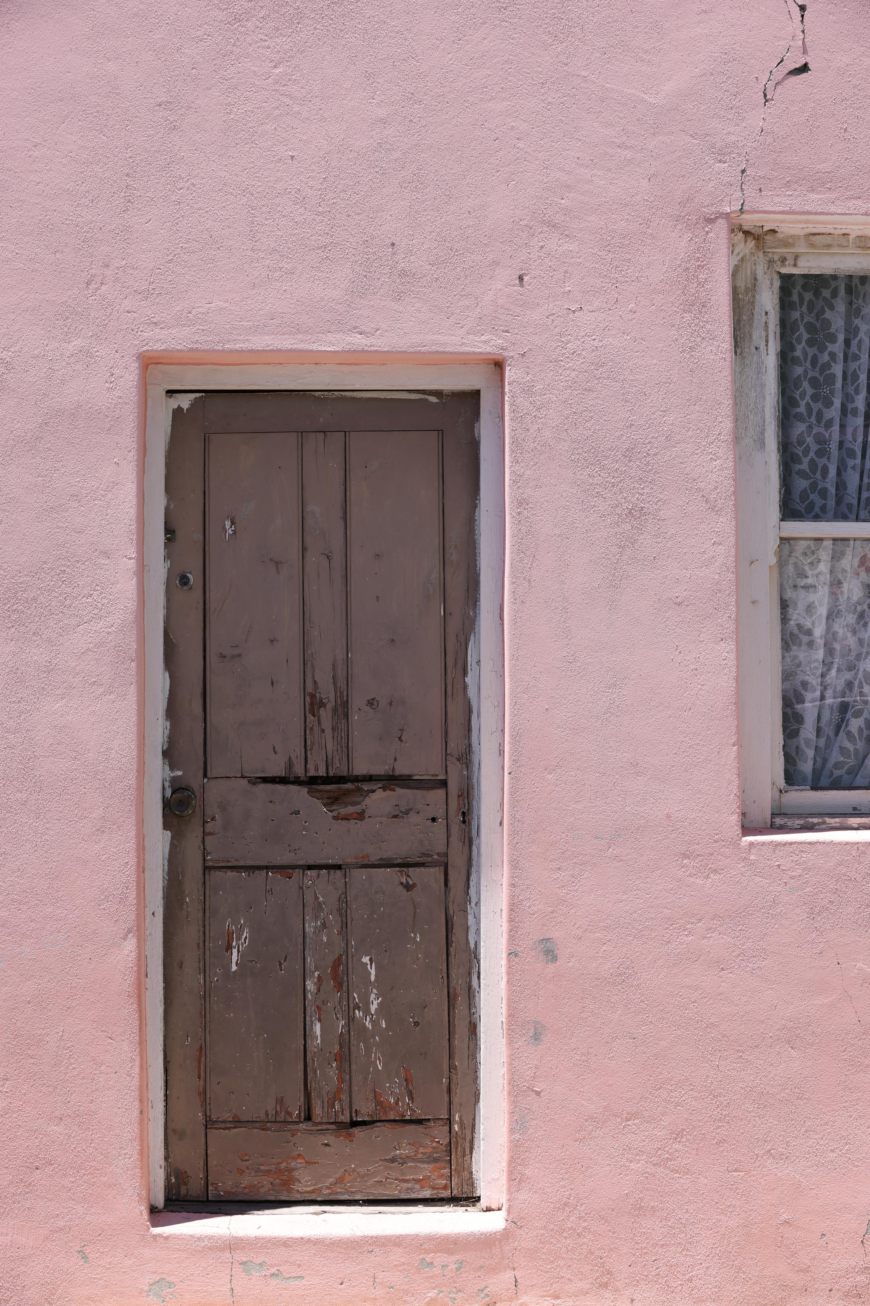 Spritzschutz-Verwitterte Holztür an rosa Bauernhaus