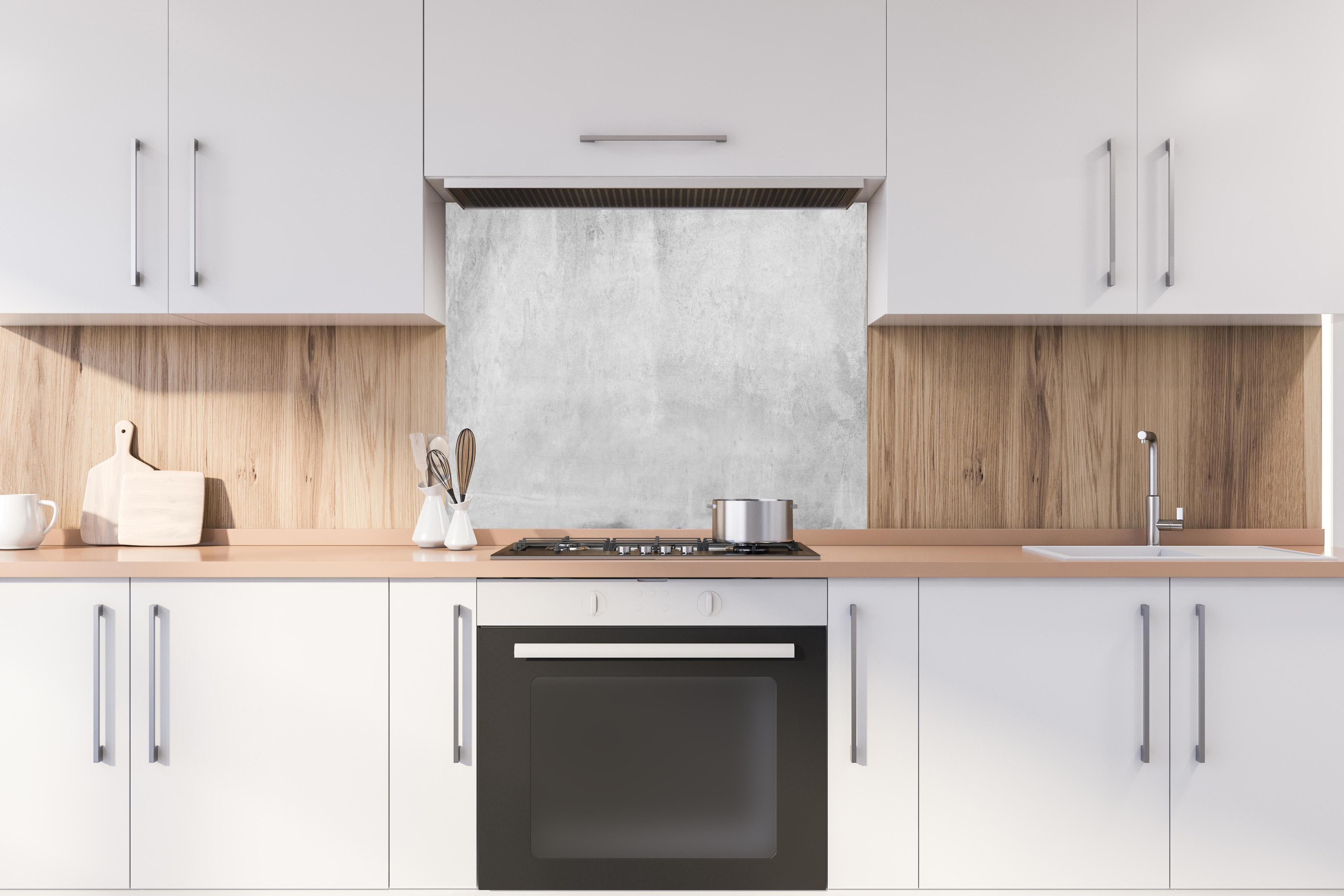 Spritzschutz - Verwitterte graue Zementwand hinter einem Cerankochfeld zwischen Holz-Kochutensilien