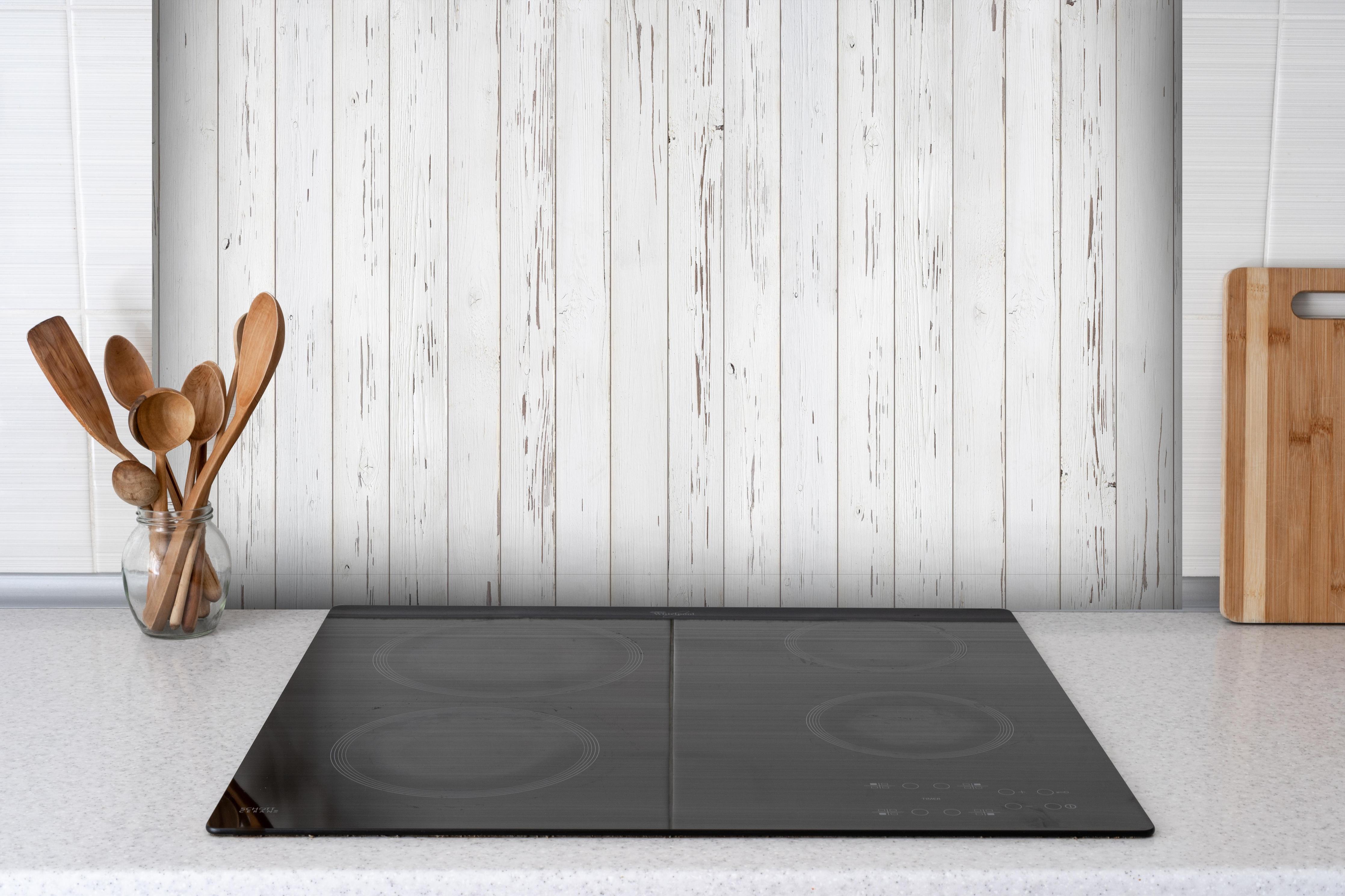 Spritzschutz - Verwitterte weiße Holzdielen hinter einem Cerankochfeld zwischen Holz-Kochutensilien