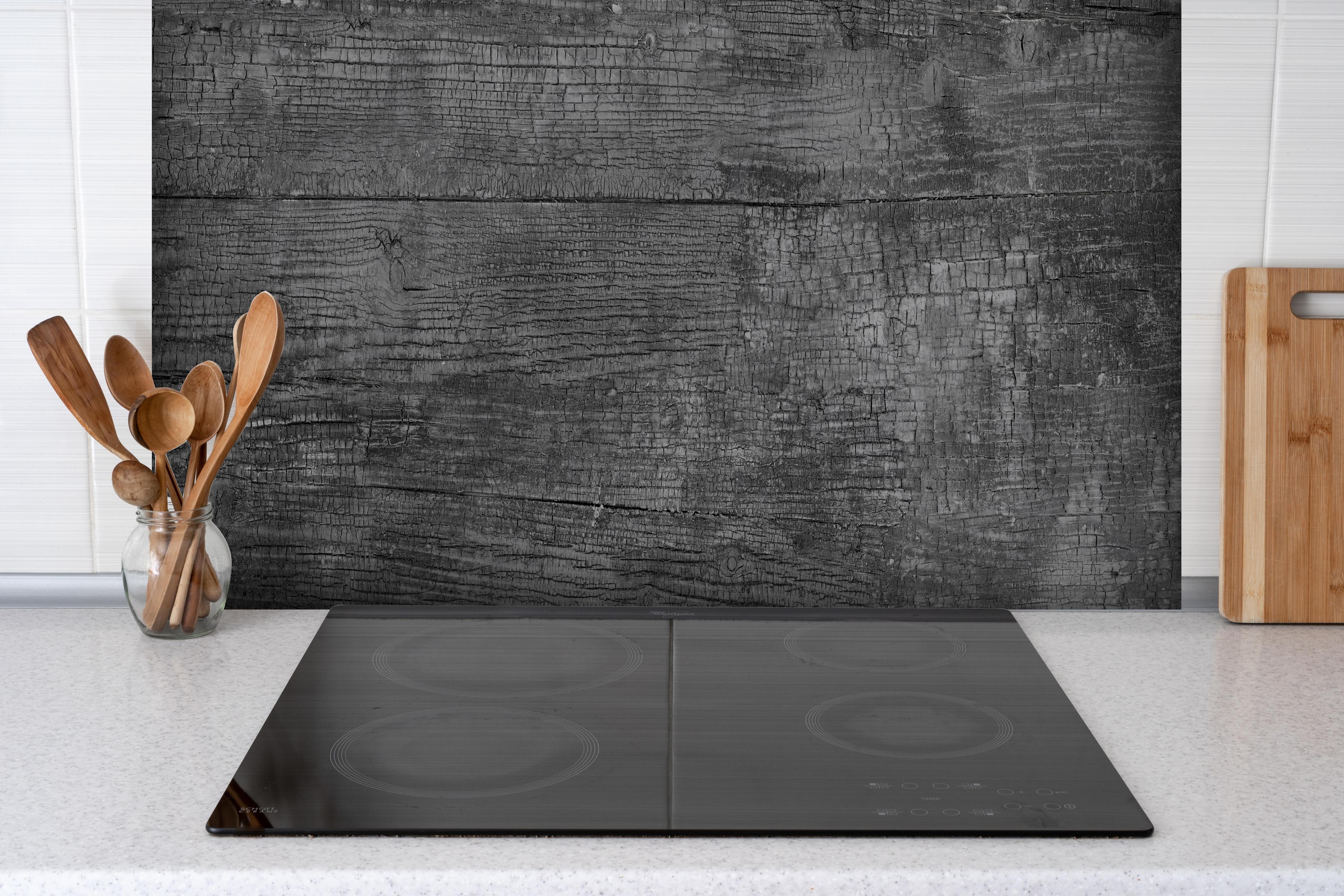 Spritzschutz - Vintage Schwarz-Graue Altholz-Textur hinter einem Cerankochfeld zwischen Holz-Kochutensilien