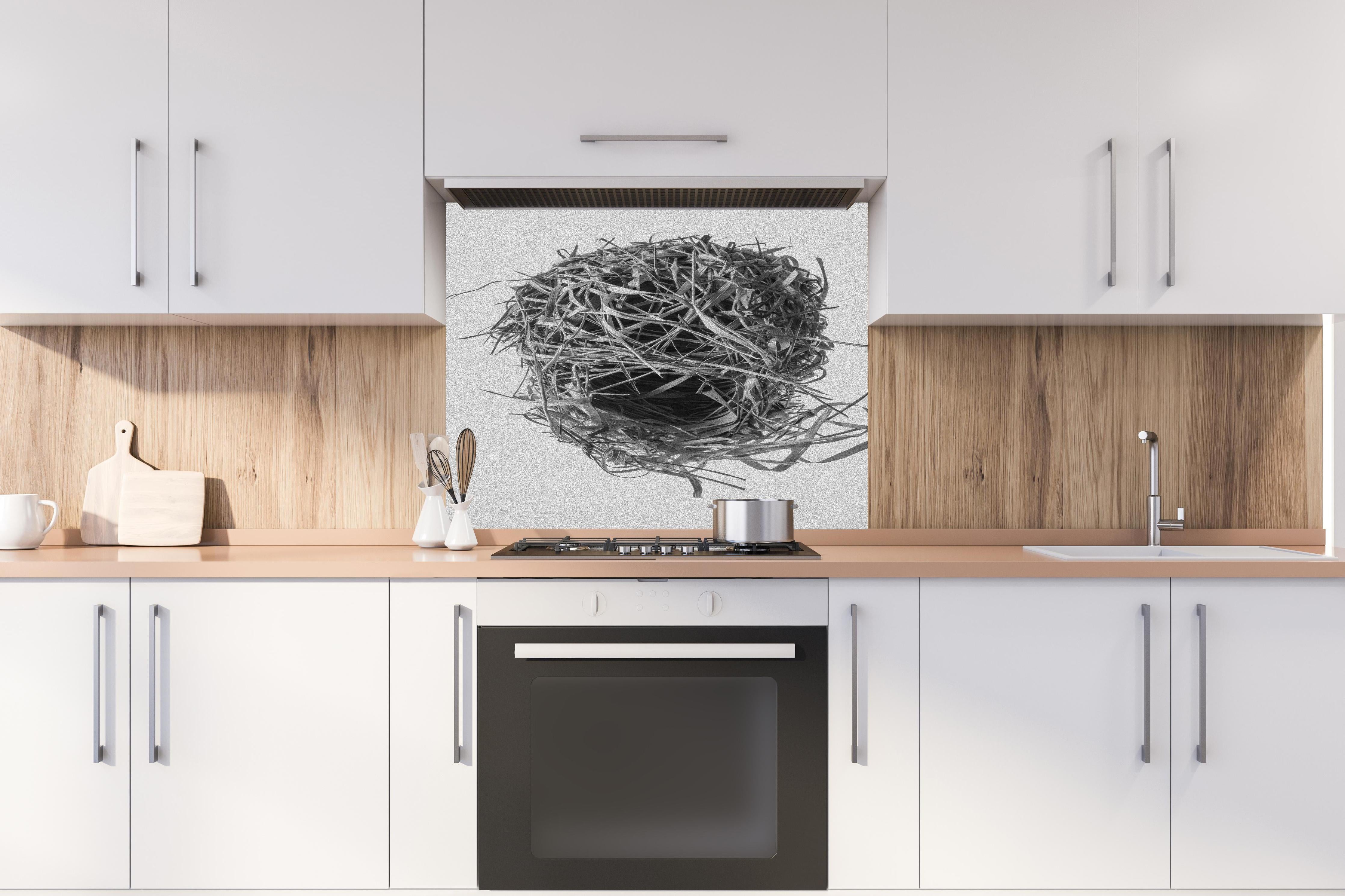 Spritzschutz - Vogelnest - schwarz-weiß hinter einem Cerankochfeld zwischen Holz-Kochutensilien