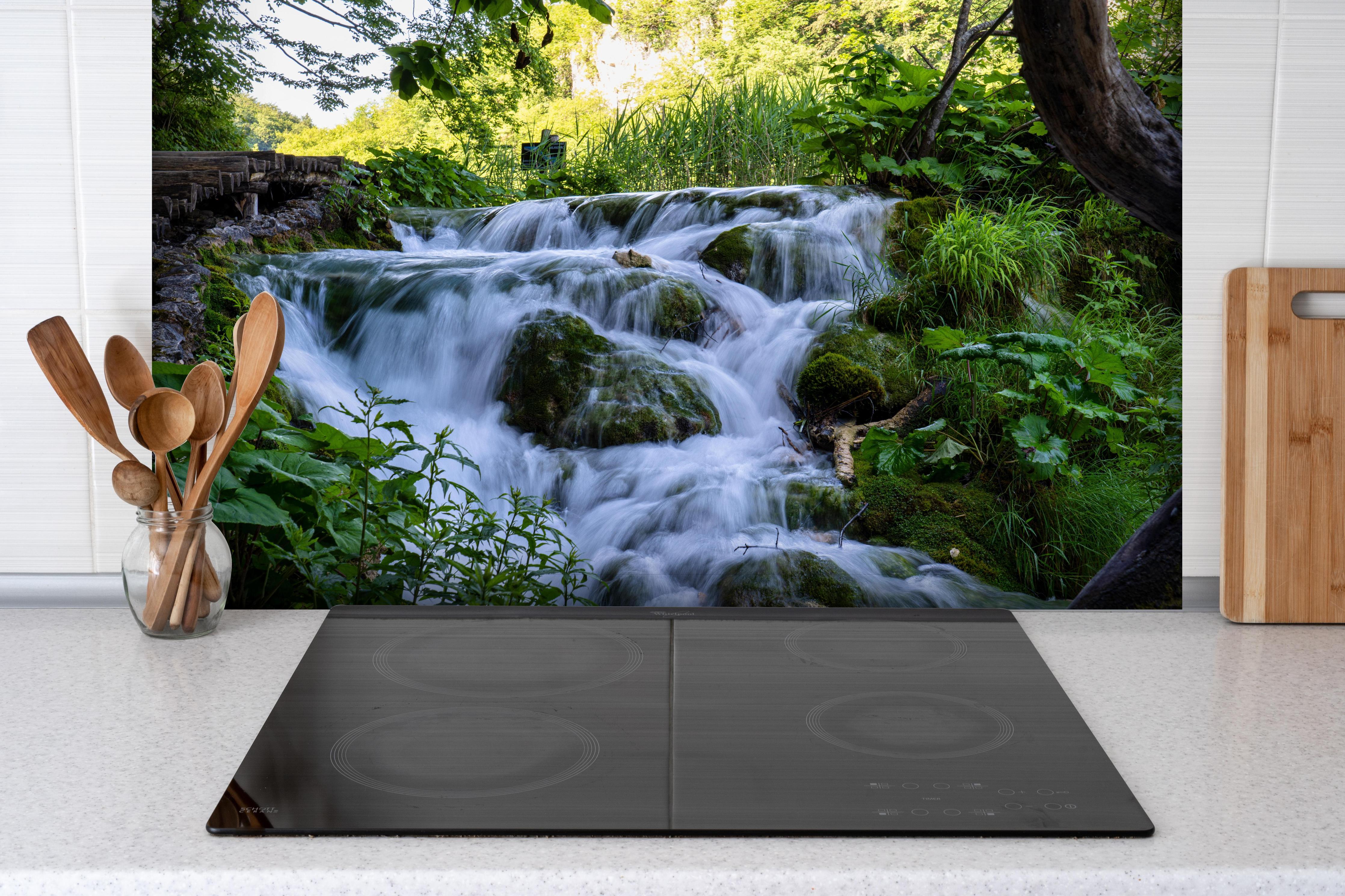 Spritzschutz - Wasserfall im Nationalpark Plitvicer Seen hinter einem Cerankochfeld zwischen Holz-Kochutensilien