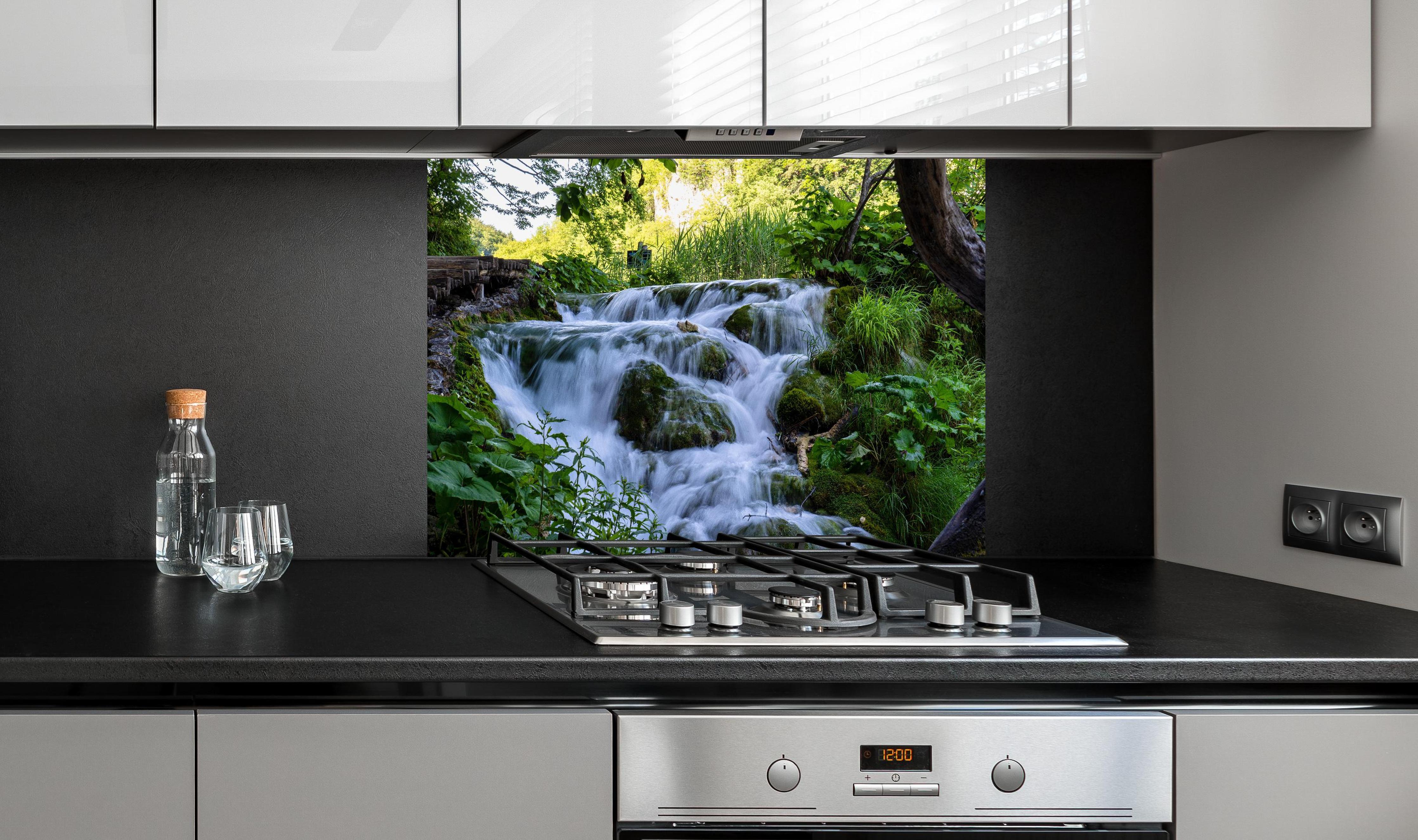 Spritzschutz - Wasserfall im Nationalpark Plitvicer Seen hinter einem Cerankochfeld zwischen Holz-Kochutensilien