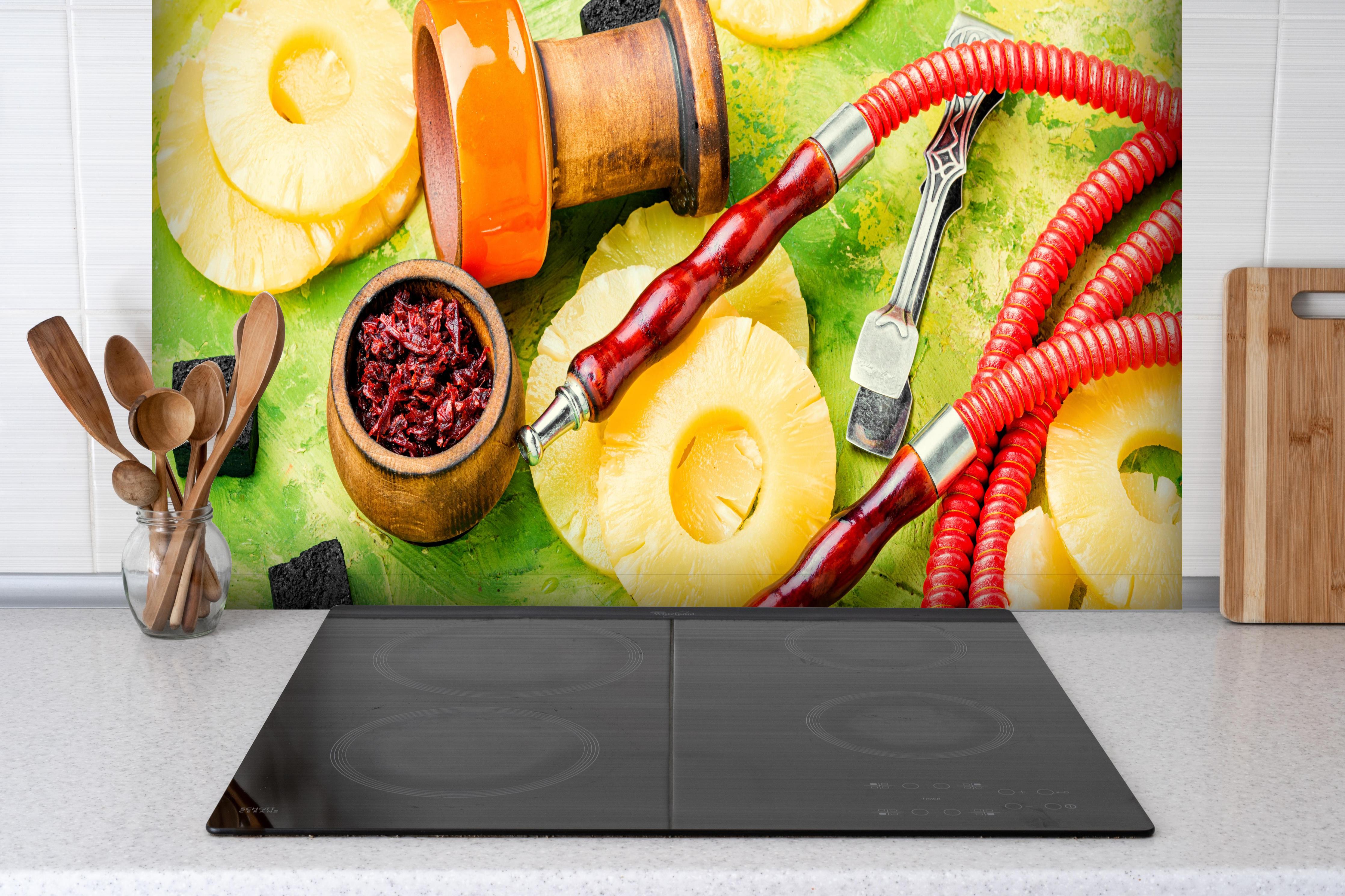 Spritzschutz - Wasserpfeife mit Ananas-Aroma. hinter einem Cerankochfeld zwischen Holz-Kochutensilien