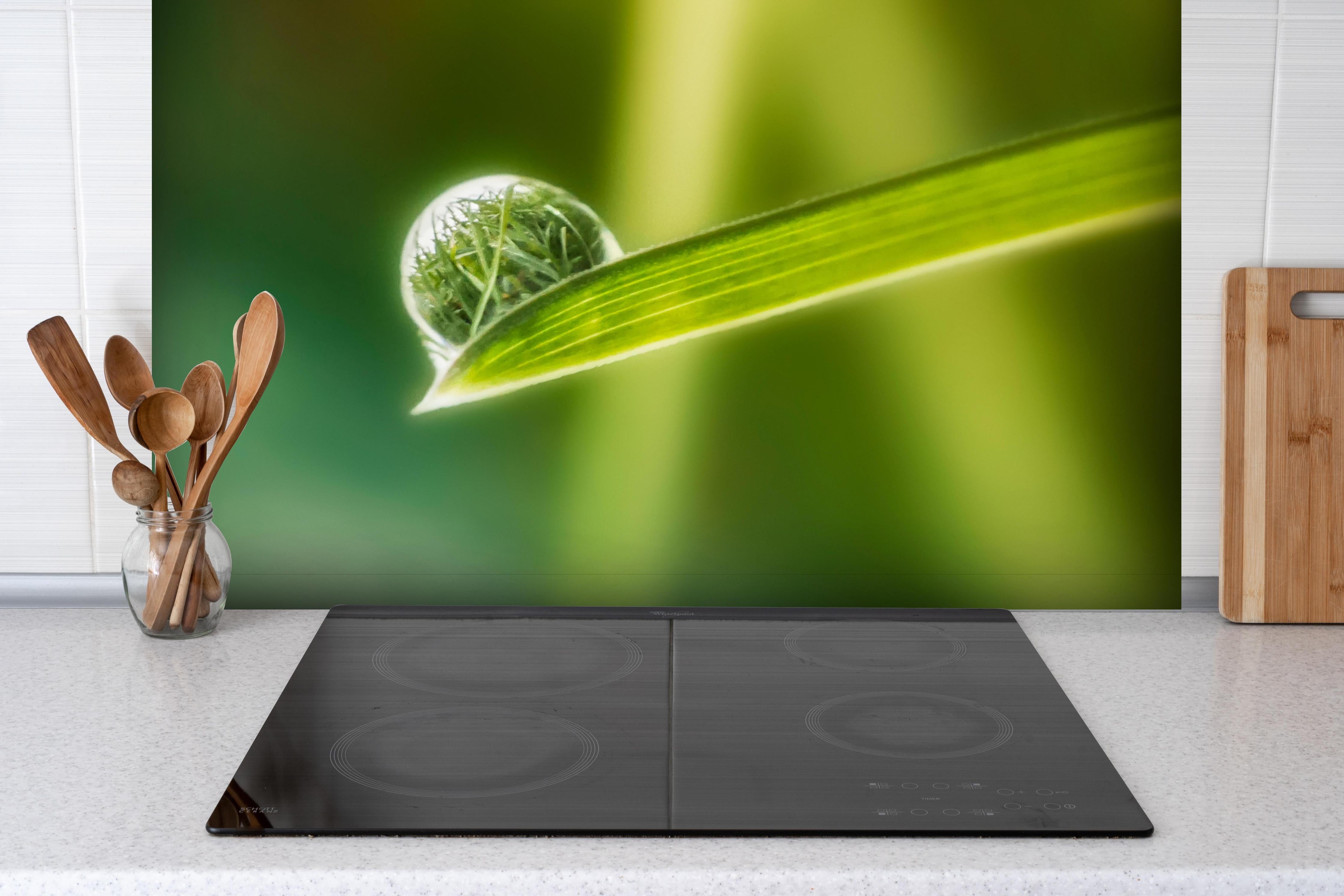 Spritzschutz - Wassertropfen hinter einem Cerankochfeld zwischen Holz-Kochutensilien