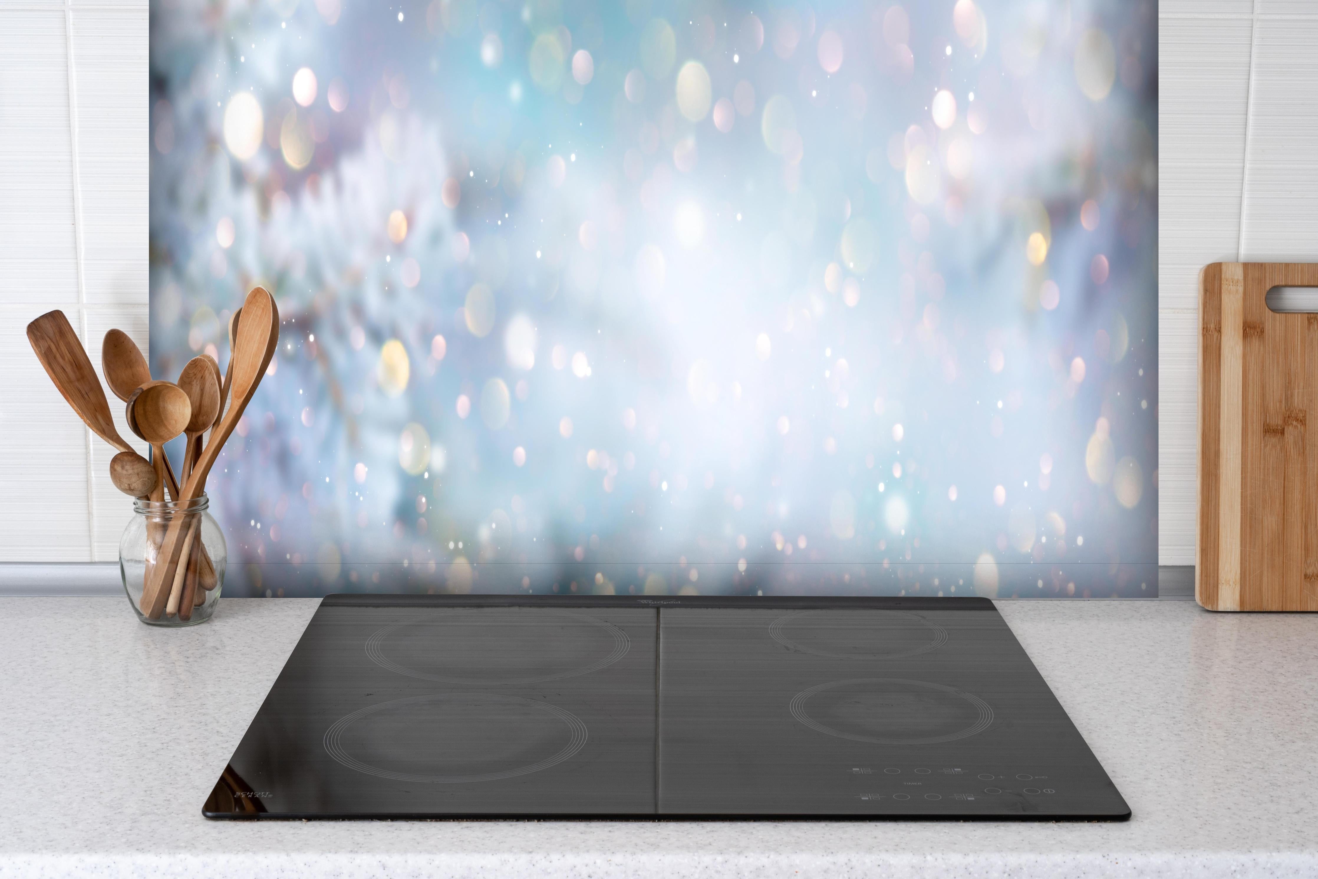 Spritzschutz - Weihnachtlicher Hintergrund mit Licht und Schnee hinter einem Cerankochfeld zwischen Holz-Kochutensilien