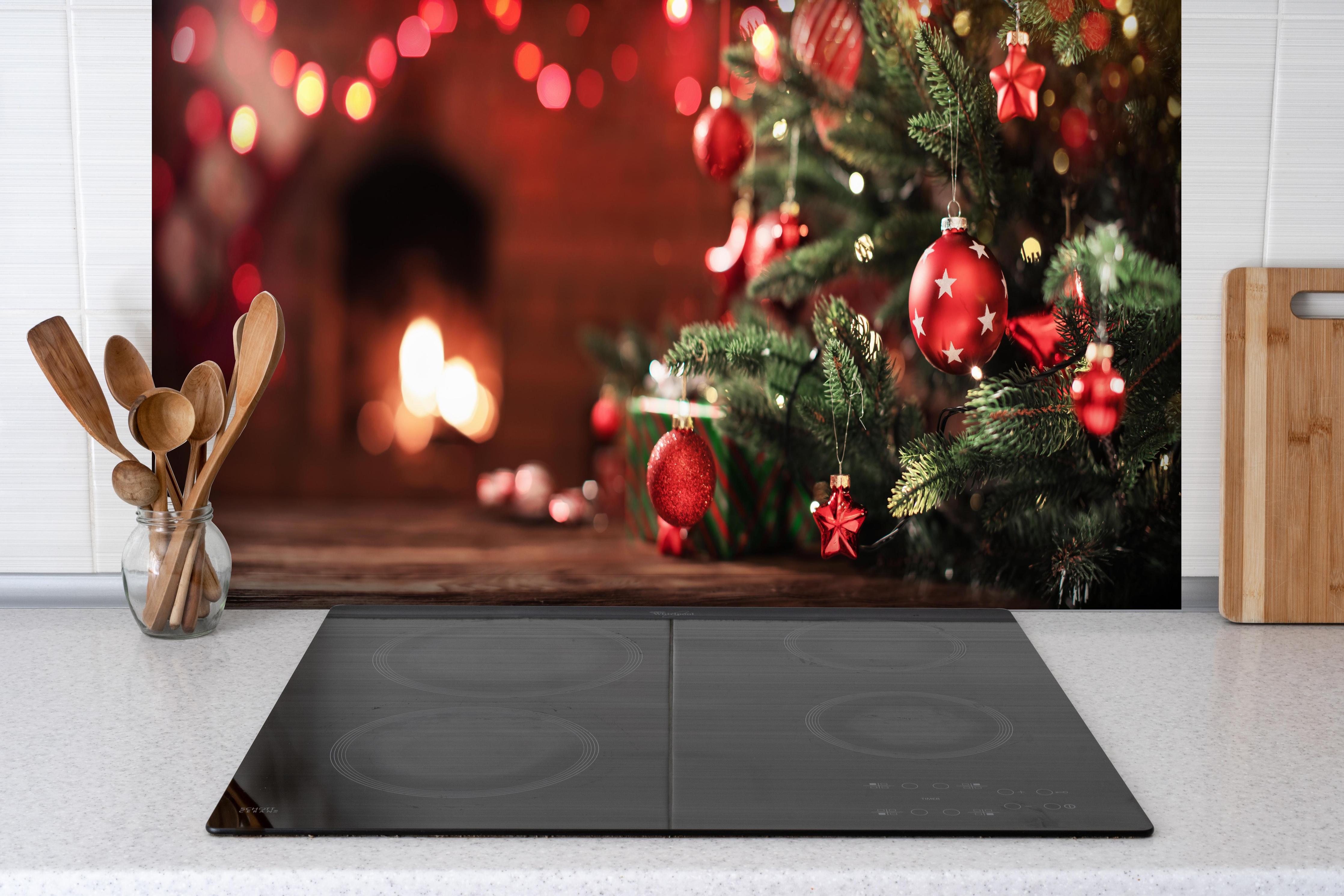 Spritzschutz - Weihnachtsbaum mit Dekorationen hinter einem Cerankochfeld zwischen Holz-Kochutensilien