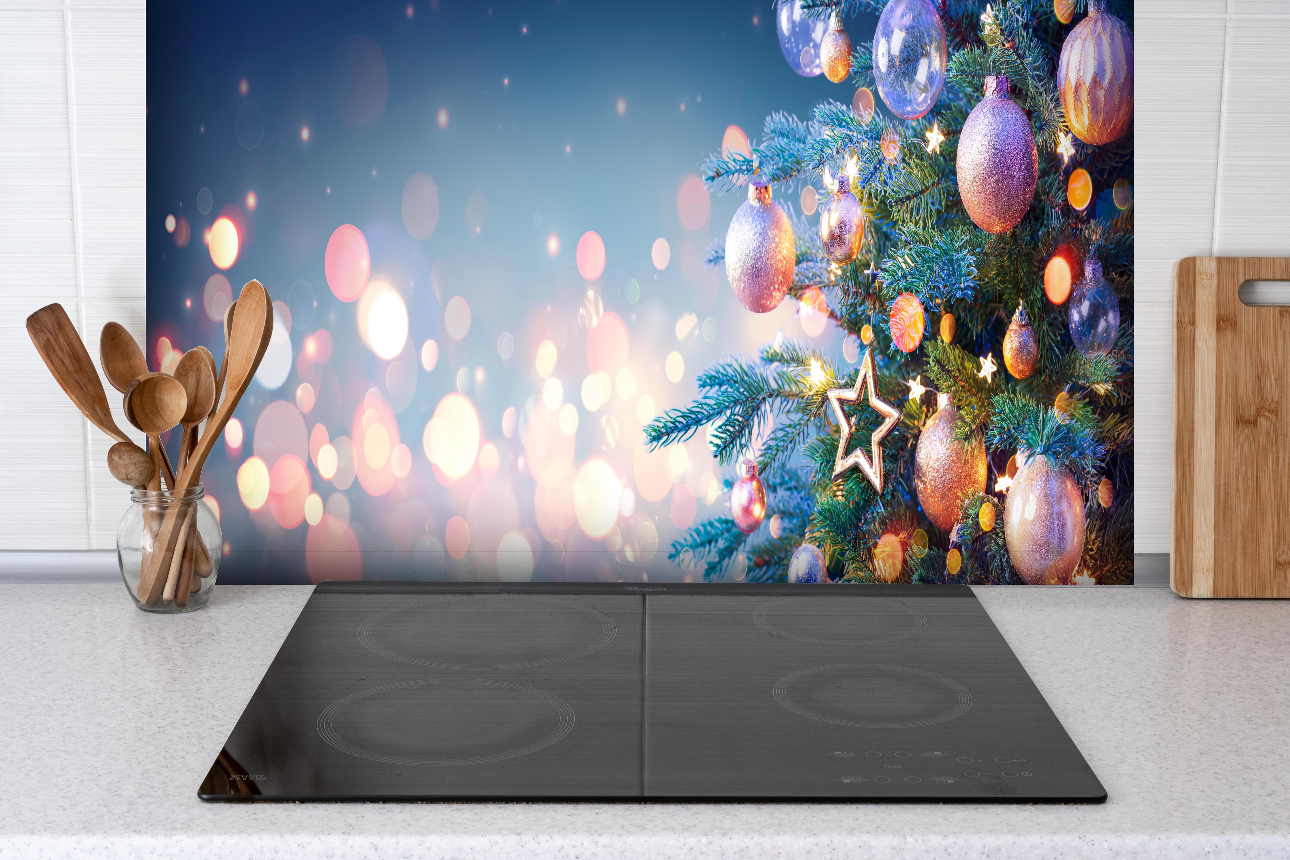 Spritzschutz - Weihnachtsbaum mit bunten Kugeln hinter einem Cerankochfeld zwischen Holz-Kochutensilien