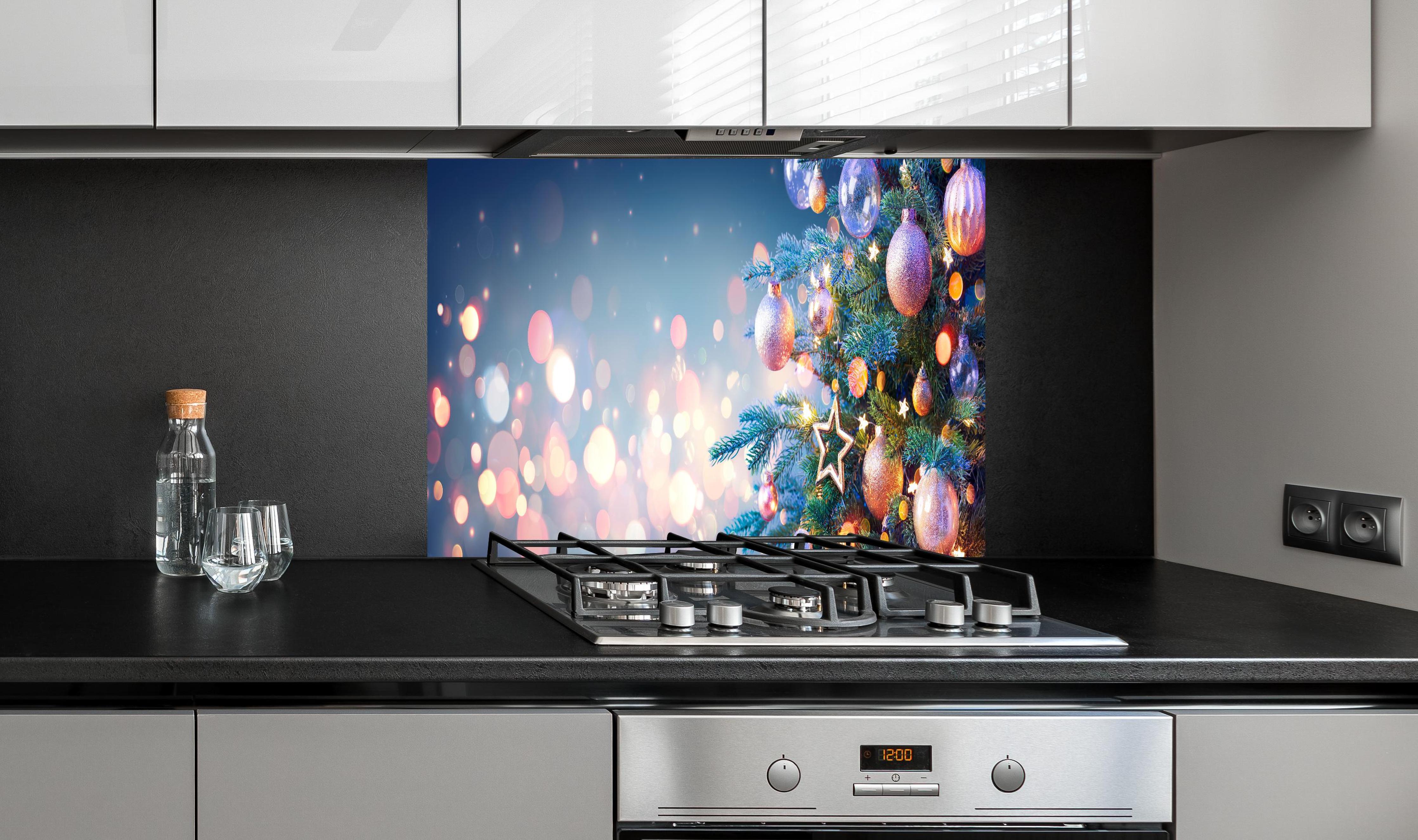 Spritzschutz - Weihnachtsbaum mit bunten Kugeln hinter einem Cerankochfeld zwischen Holz-Kochutensilien