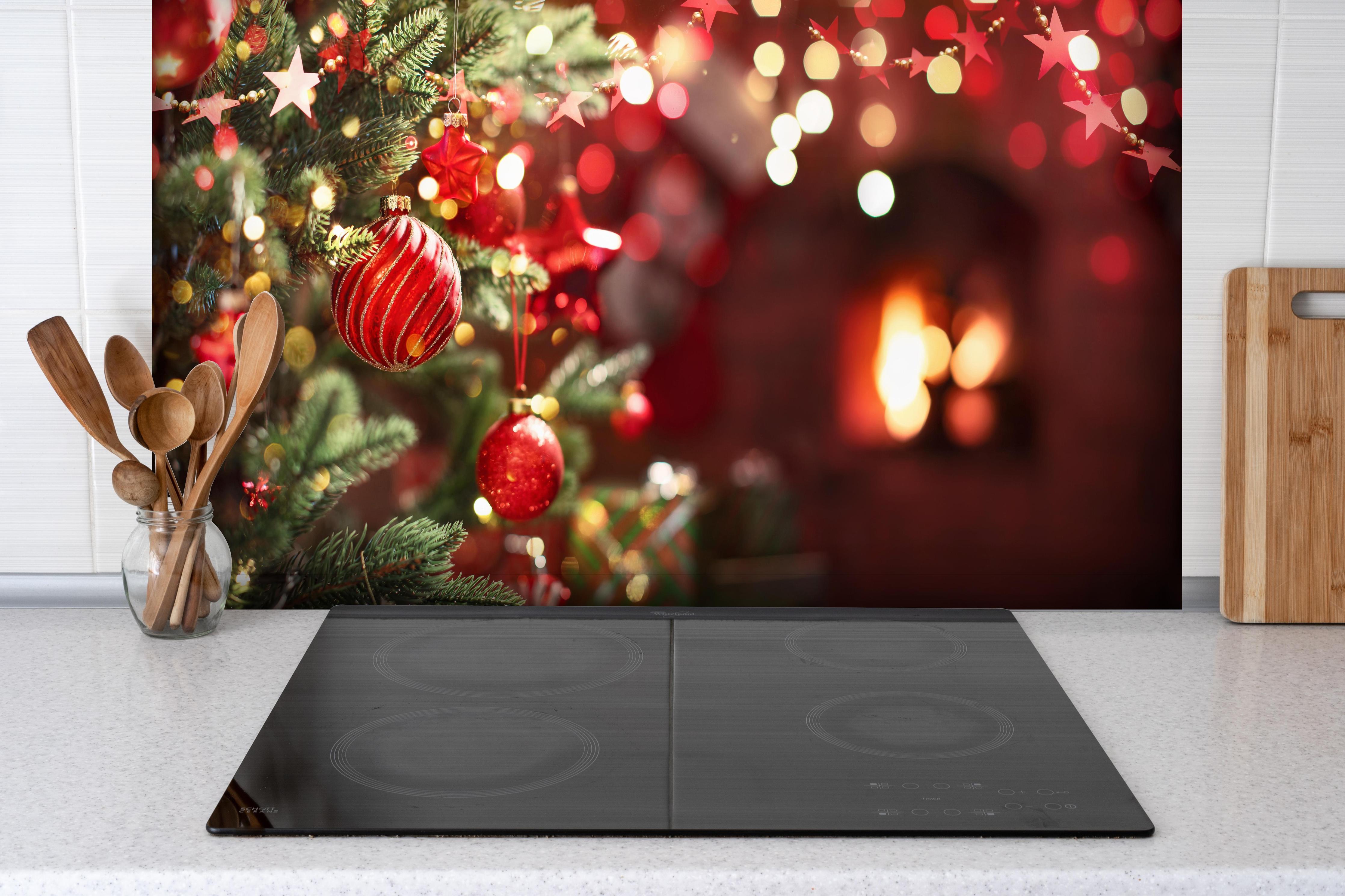 Spritzschutz - Weihnachtsbaum mit roten Kugeln und Sternen hinter einem Cerankochfeld zwischen Holz-Kochutensilien
