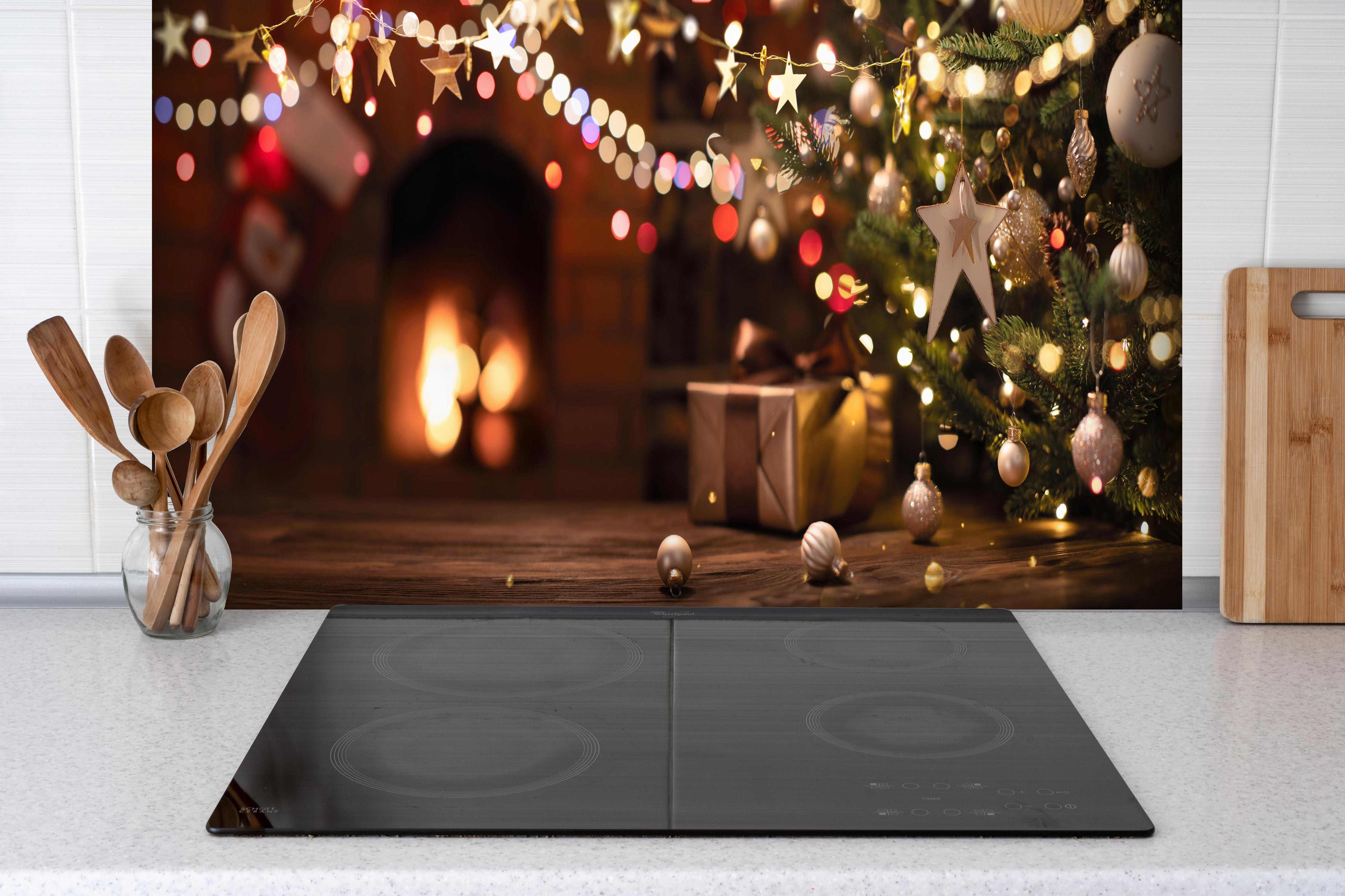 Spritzschutz - Weihnachtsbaum, Sterne und festliche Lichter hinter einem Cerankochfeld zwischen Holz-Kochutensilien