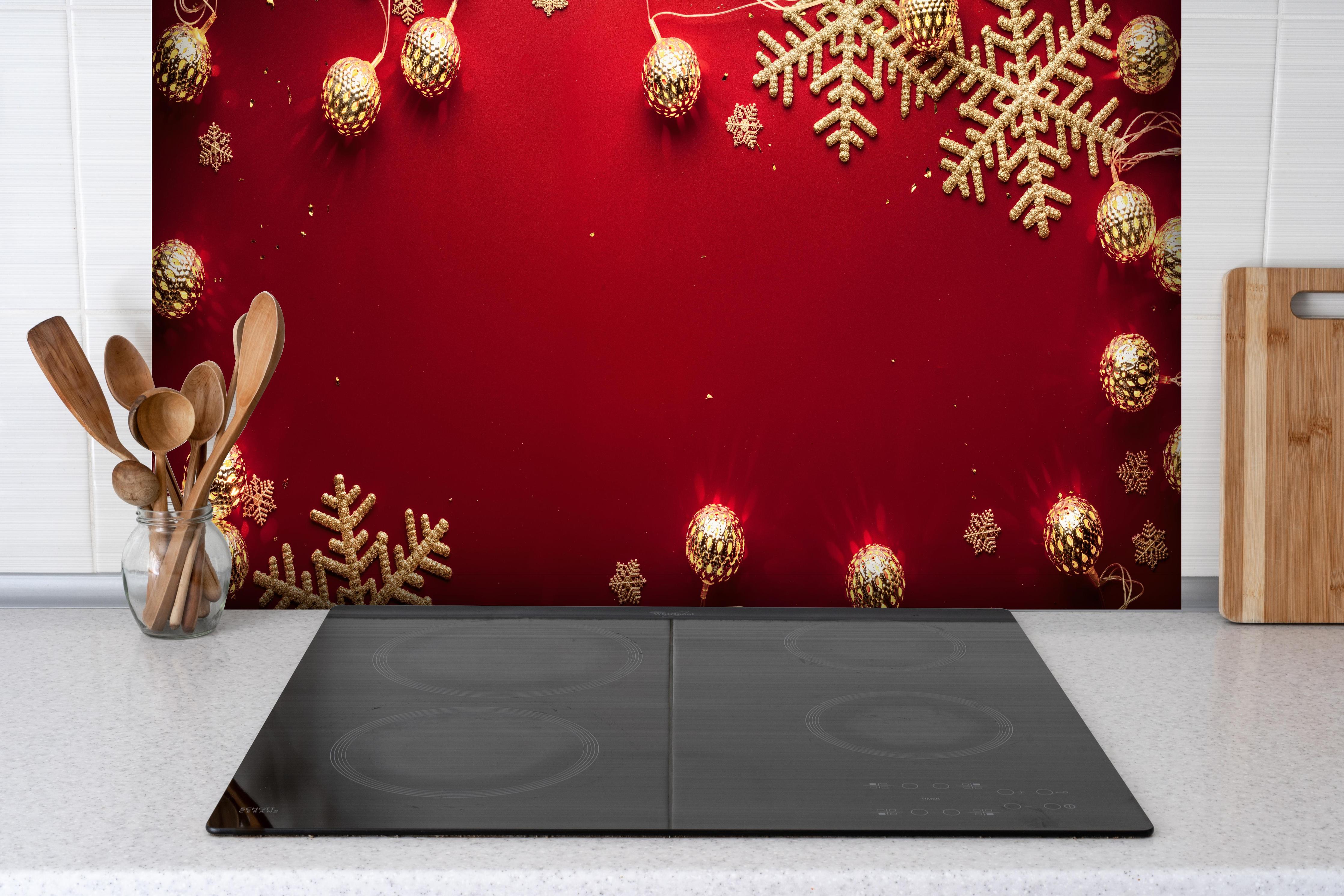 Spritzschutz - Weihnachtsdekoration auf rotem Hintergrund hinter einem Cerankochfeld zwischen Holz-Kochutensilien