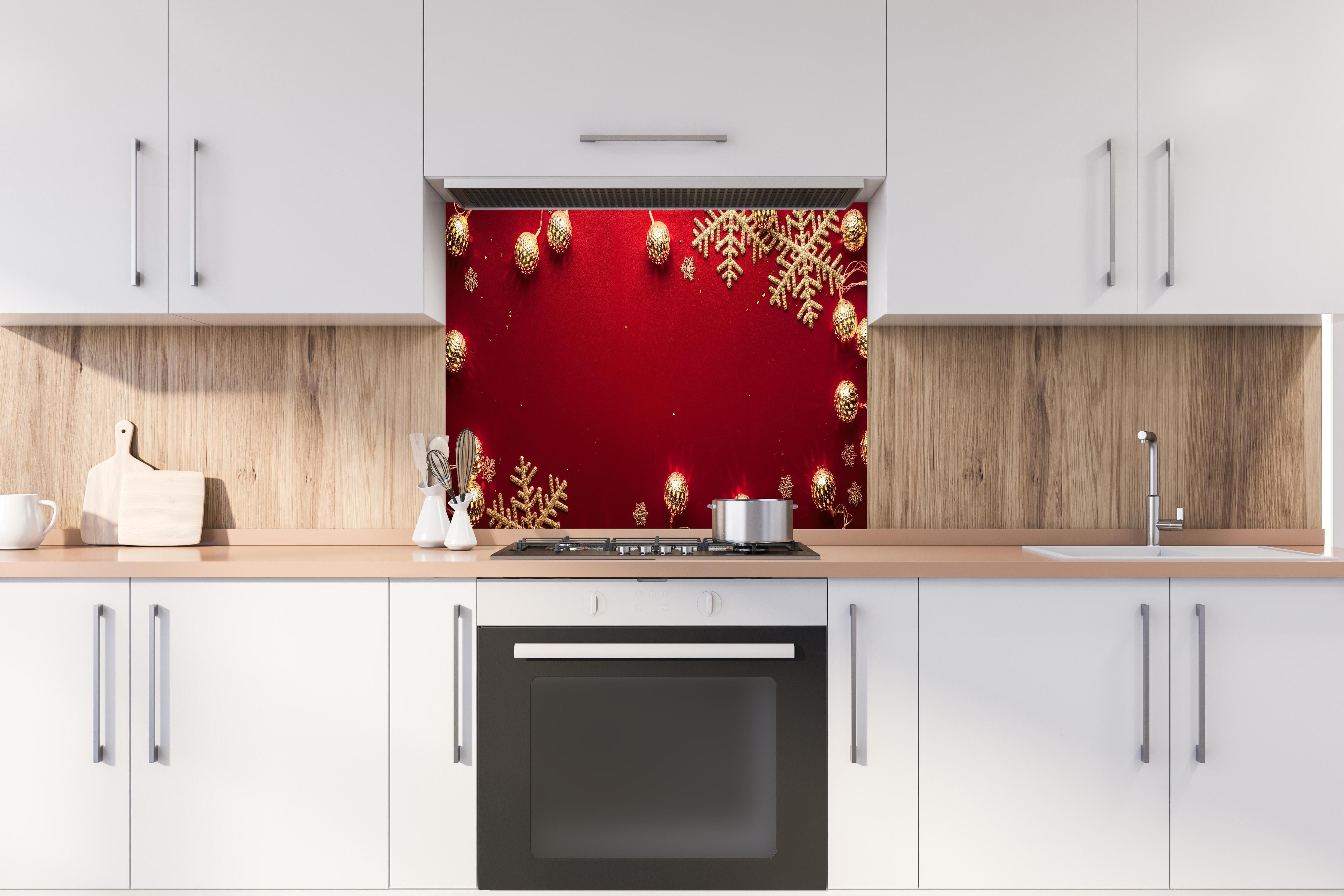 Spritzschutz - Weihnachtsdekoration auf rotem Hintergrund hinter einem Cerankochfeld zwischen Holz-Kochutensilien