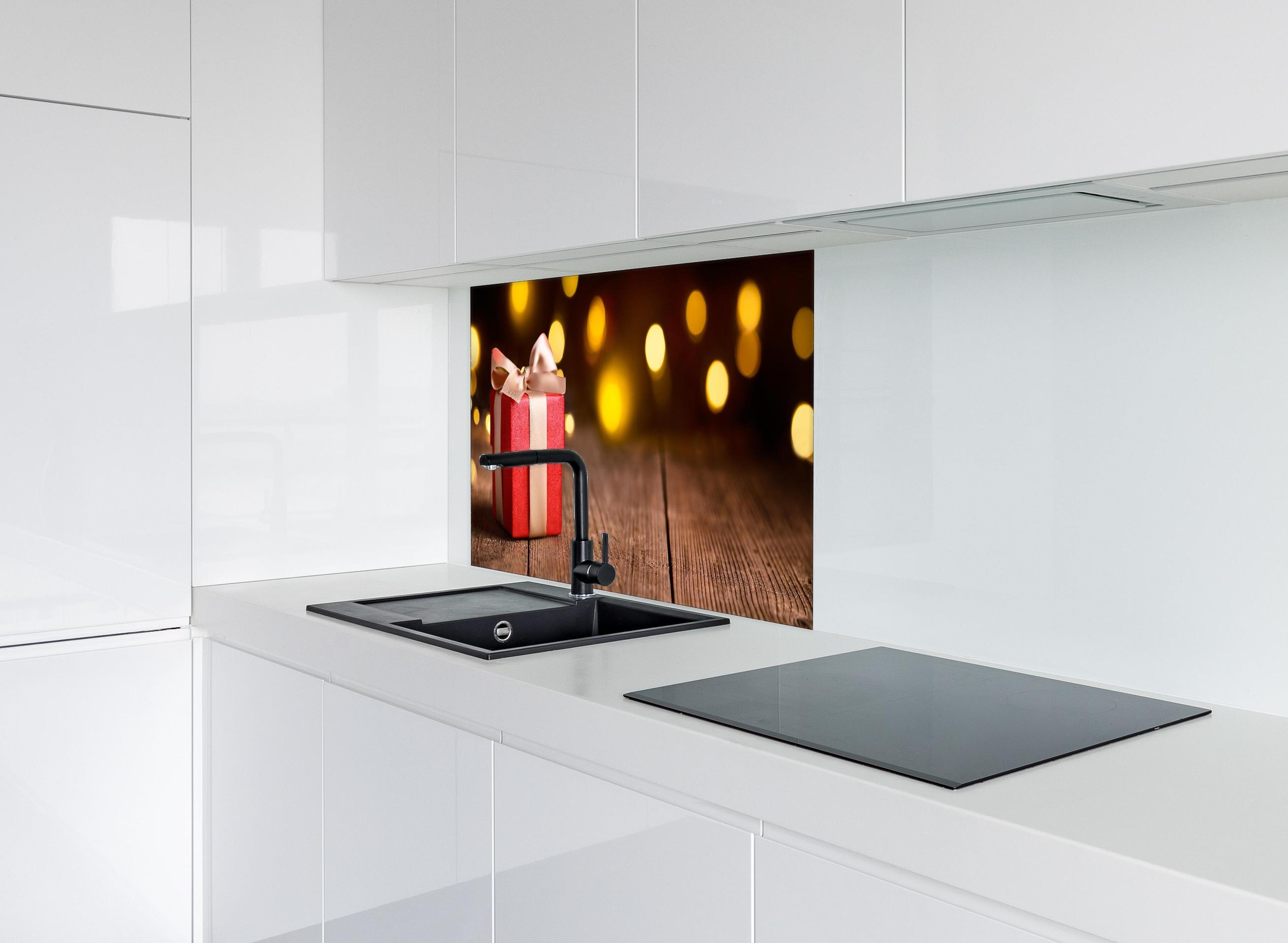 Spritzschutz - Weihnachtsgeschenk auf festlichem Hintergrund hinter einem Cerankochfeld zwischen Holz-Kochutensilien