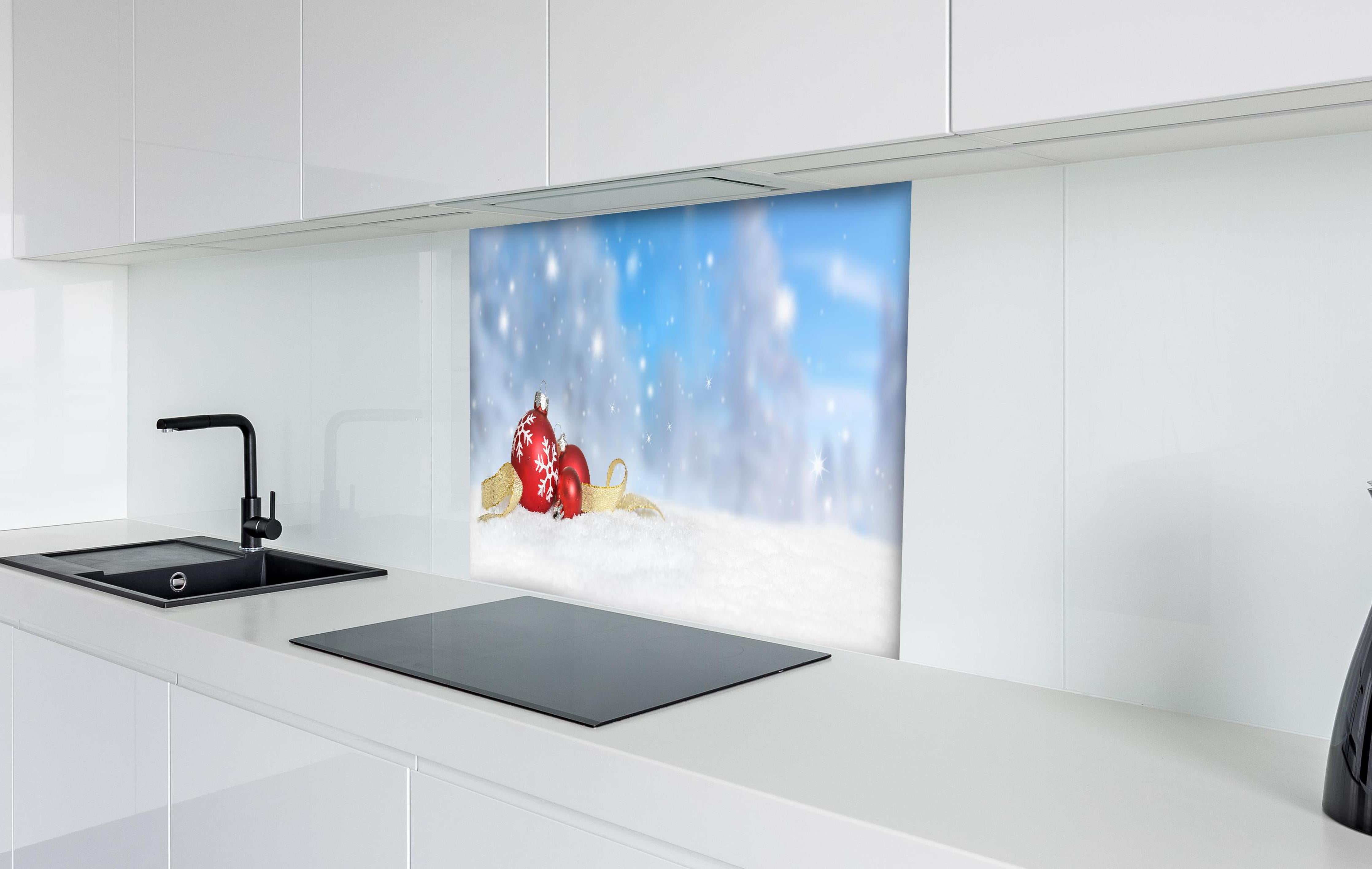 Spritzschutz - Weihnachtskugeln im Schnee hinter einem Cerankochfeld zwischen Holz-Kochutensilien