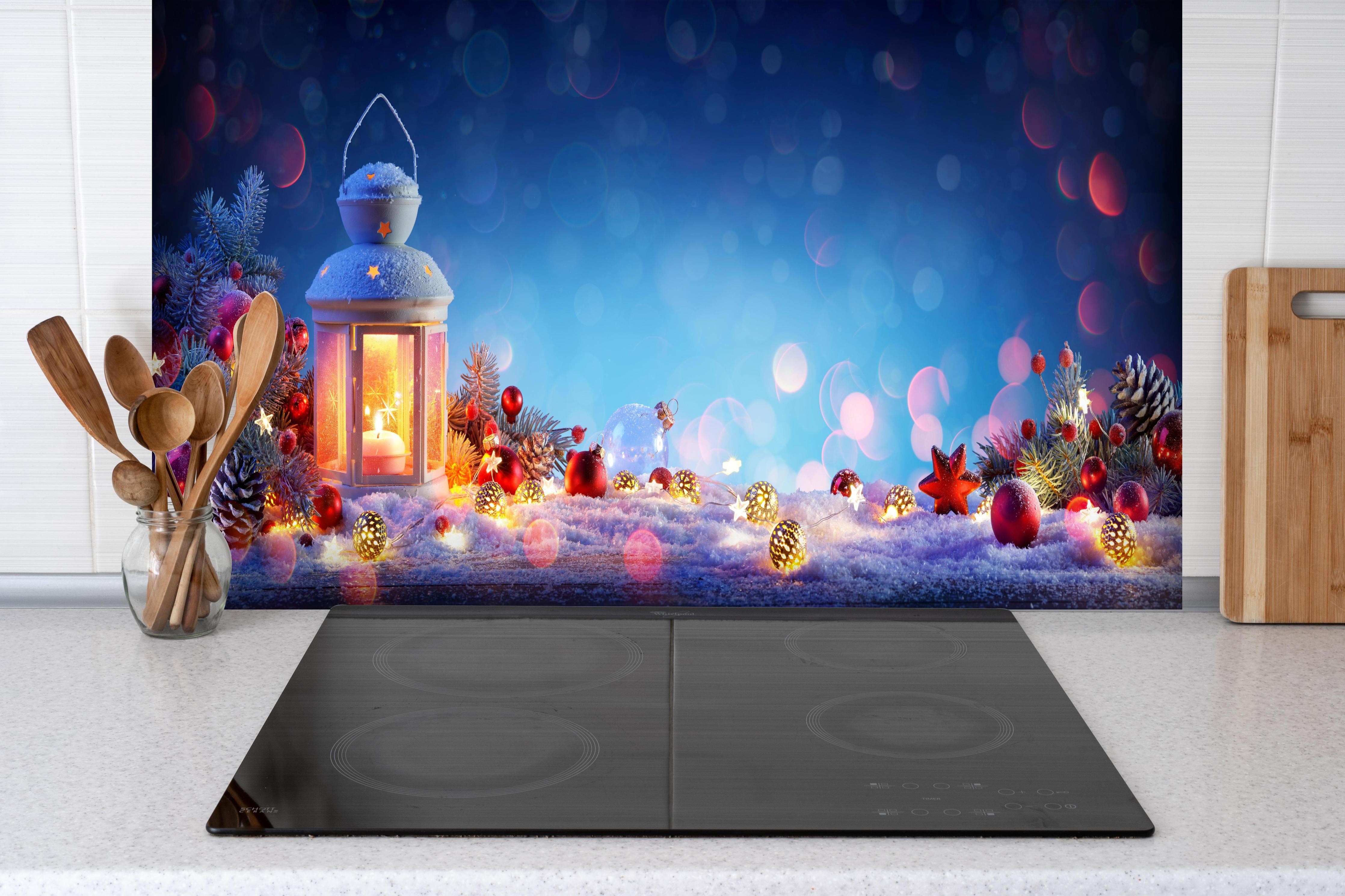 Spritzschutz - Weihnachtslaterne auf verschneiten Tisch hinter einem Cerankochfeld zwischen Holz-Kochutensilien