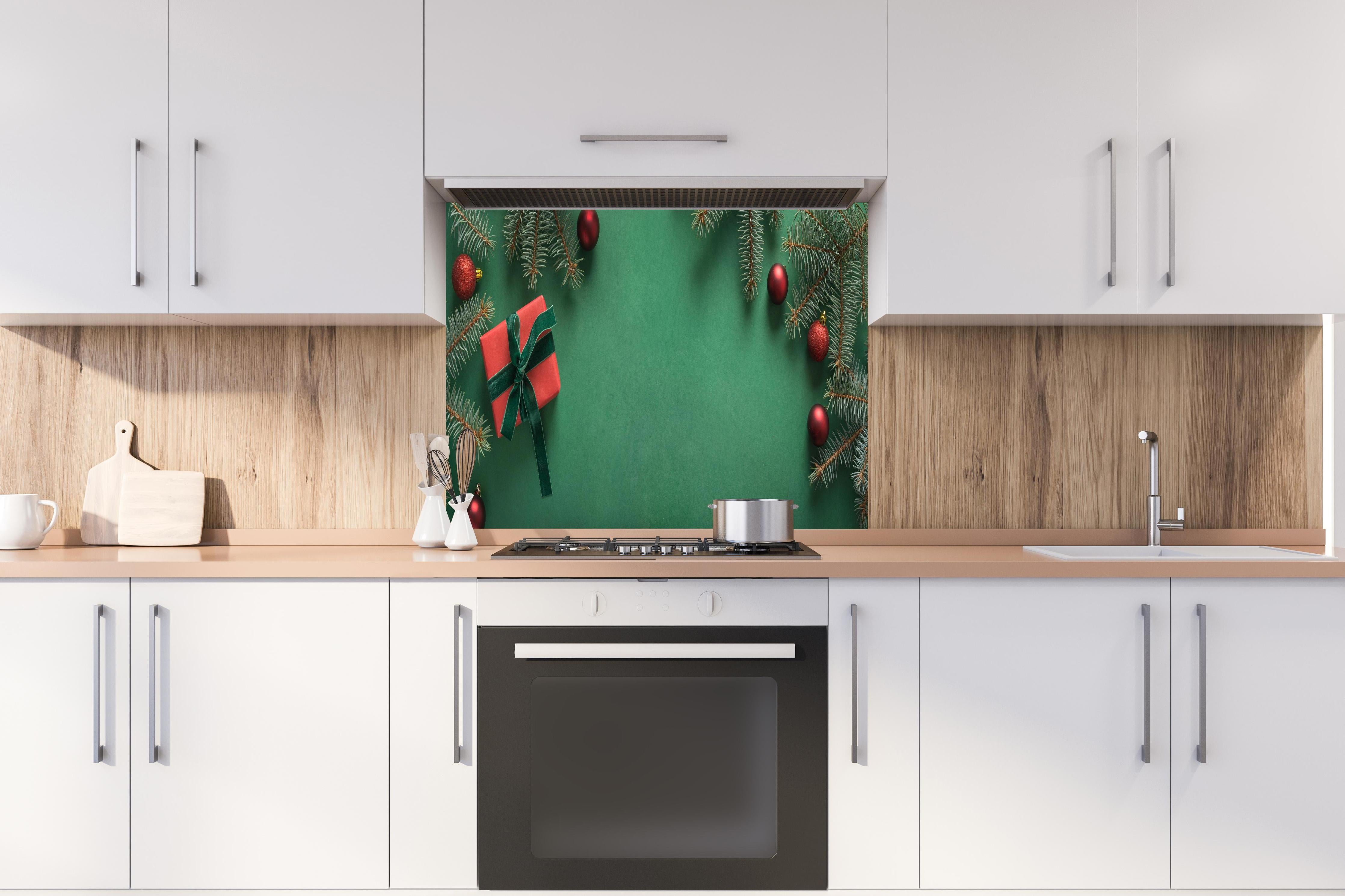 Spritzschutz - Weihnachtsrahmen auf grünem Hintergrund hinter einem Cerankochfeld zwischen Holz-Kochutensilien