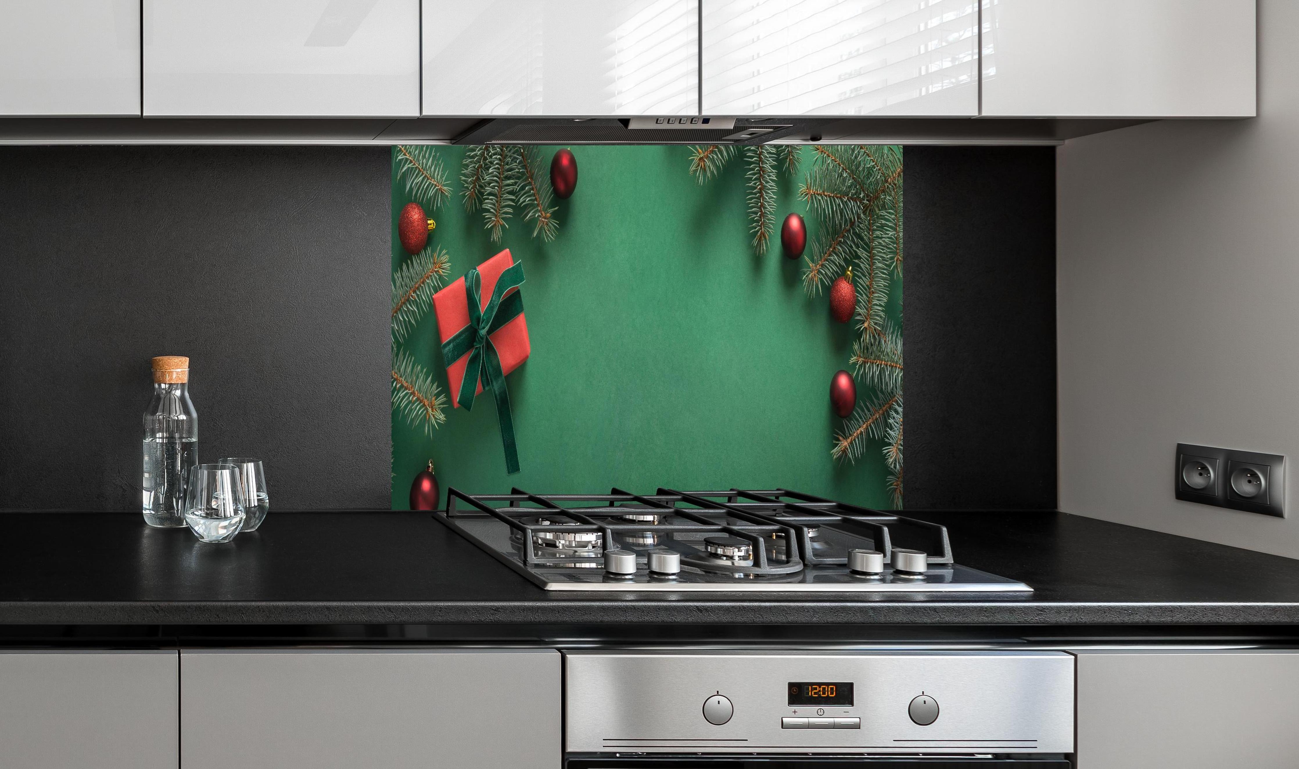 Spritzschutz - Weihnachtsrahmen auf grünem Hintergrund hinter einem Cerankochfeld zwischen Holz-Kochutensilien