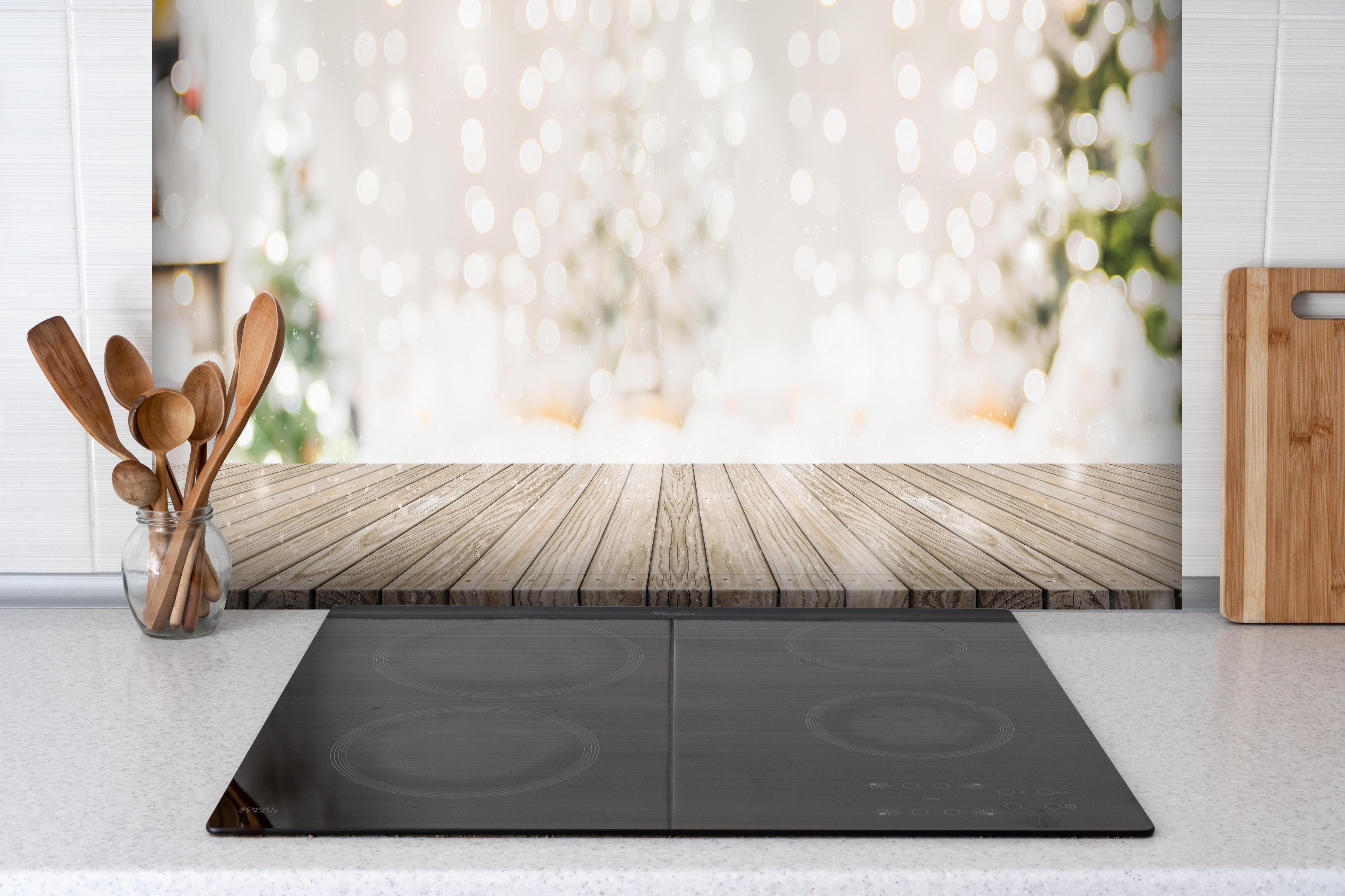 Spritzschutz - Weihnachtstimmung hinter einem Cerankochfeld zwischen Holz-Kochutensilien