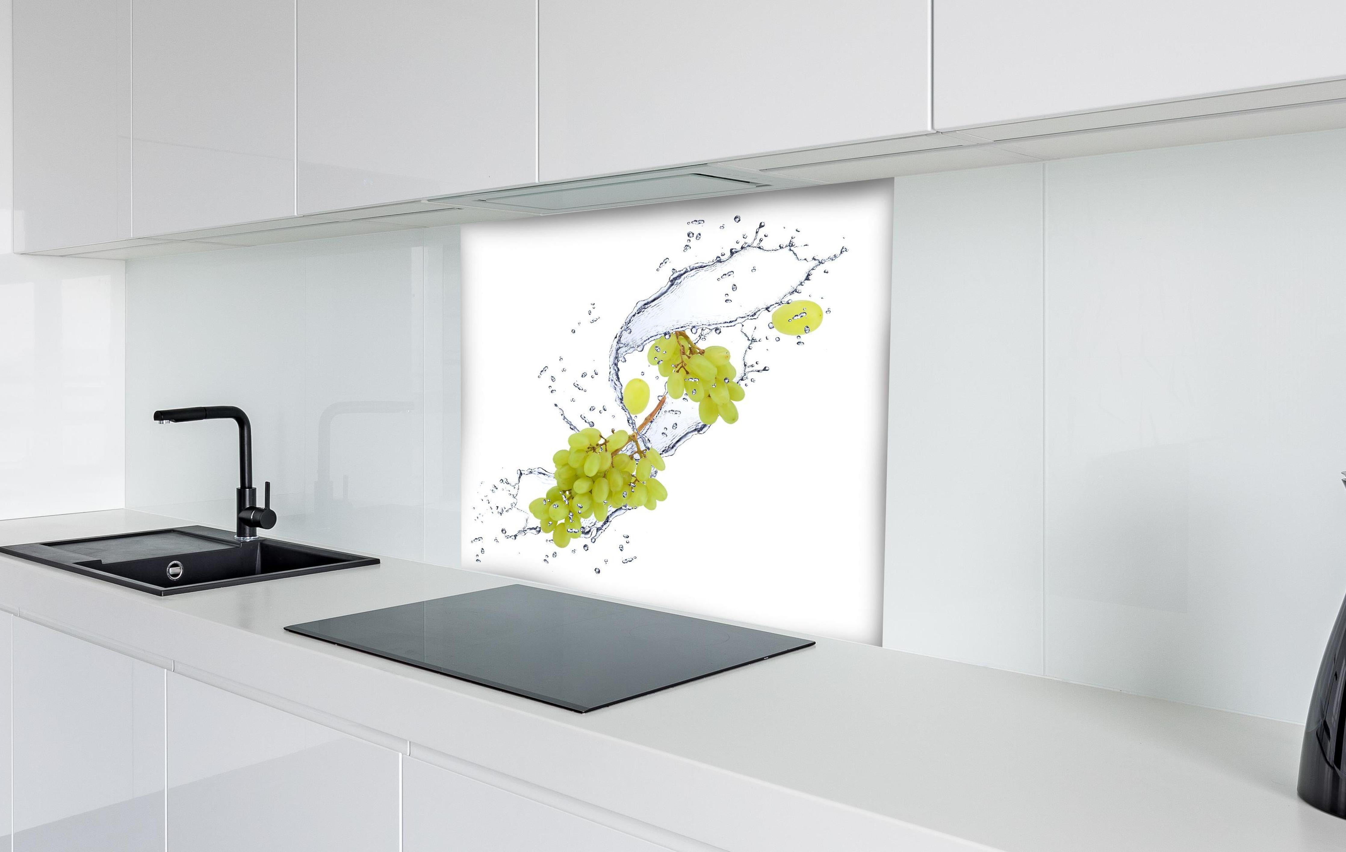 Spritzschutz - Weintraube im Wasserspritzer hinter einem Cerankochfeld zwischen Holz-Kochutensilien