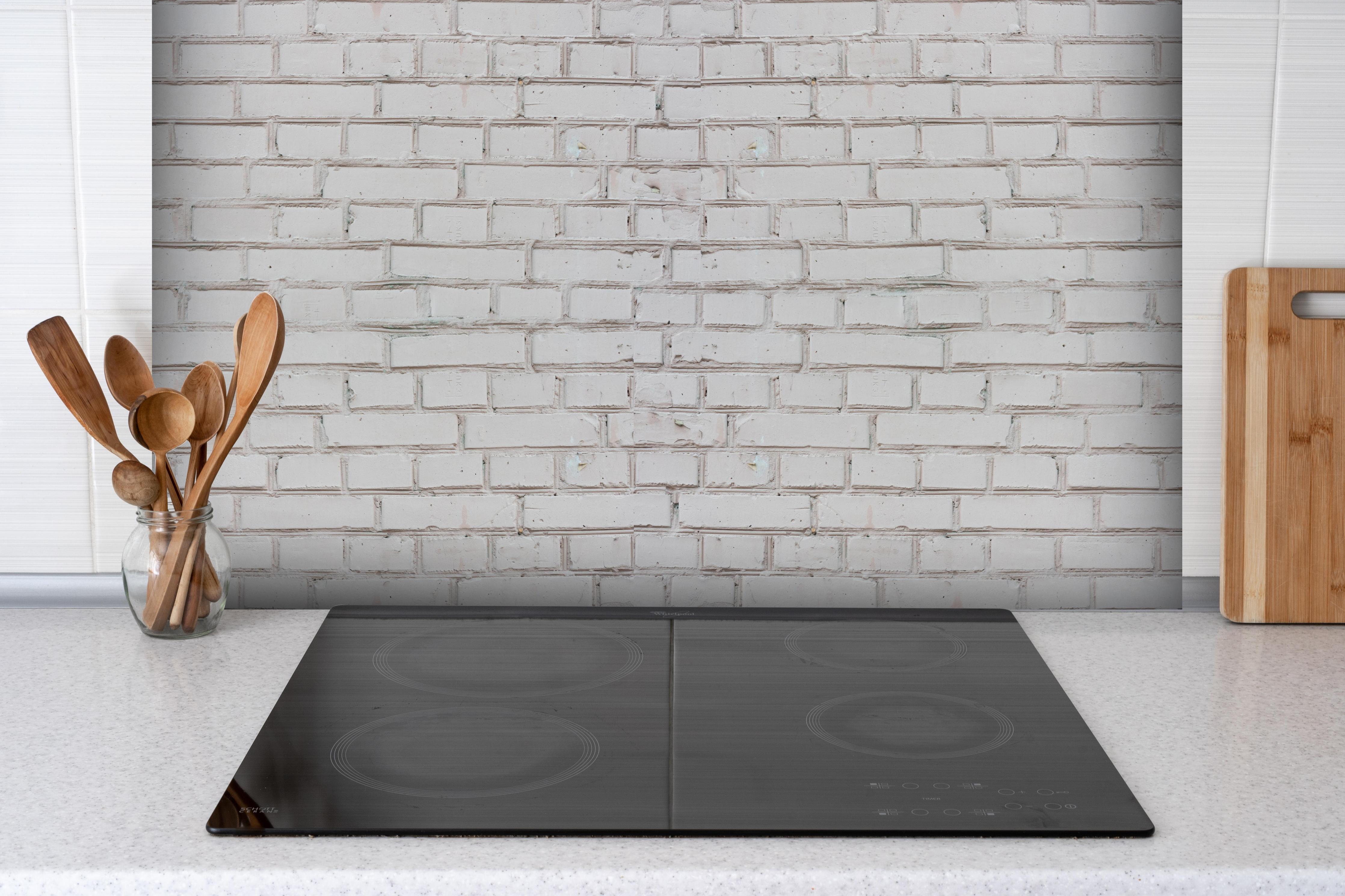 Spritzschutz - Weiß-Beige Ziegelsteinmauer hinter einem Cerankochfeld zwischen Holz-Kochutensilien