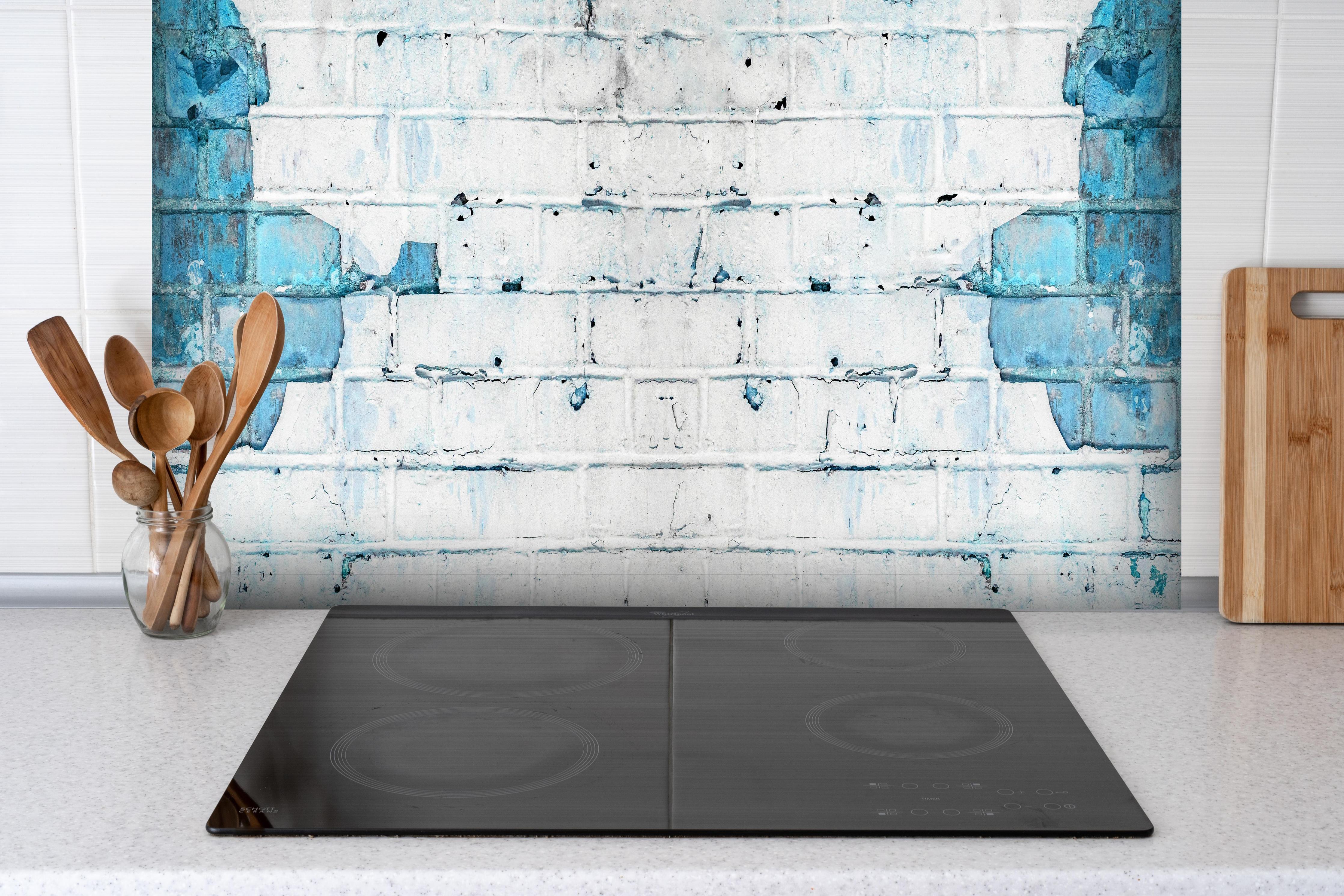 Spritzschutz - Weiß blau beschädigte Backsteinmauer hinter einem Cerankochfeld zwischen Holz-Kochutensilien
