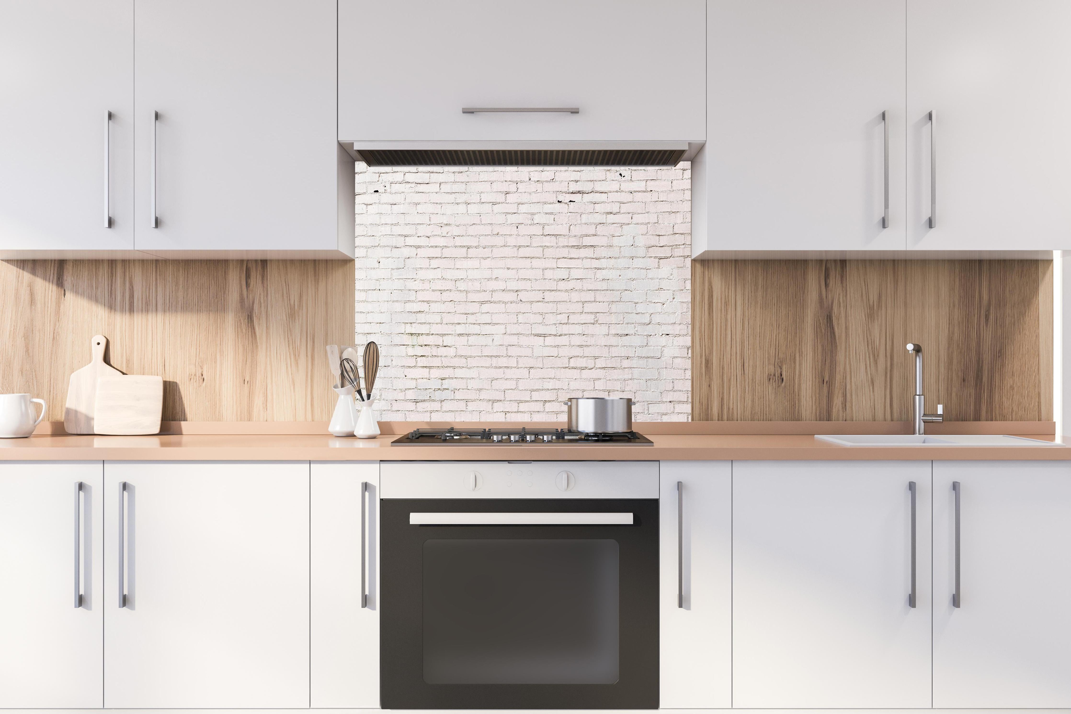 Spritzschutz - Weiß gestrichene Ziegelwand hinter einem Cerankochfeld zwischen Holz-Kochutensilien