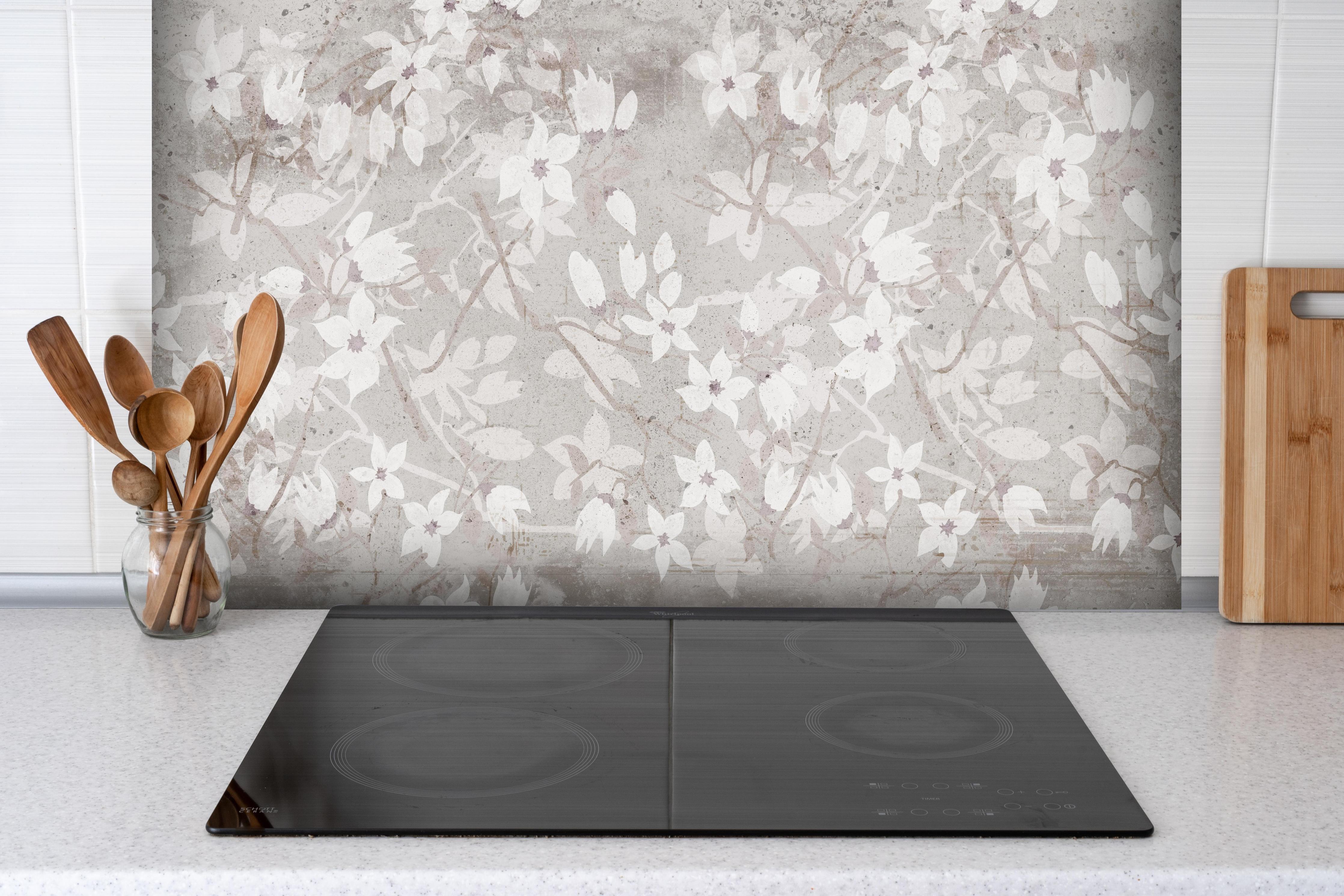 Spritzschutz - Weiße Blumen auf altem grauem Hintergrund hinter einem Cerankochfeld zwischen Holz-Kochutensilien