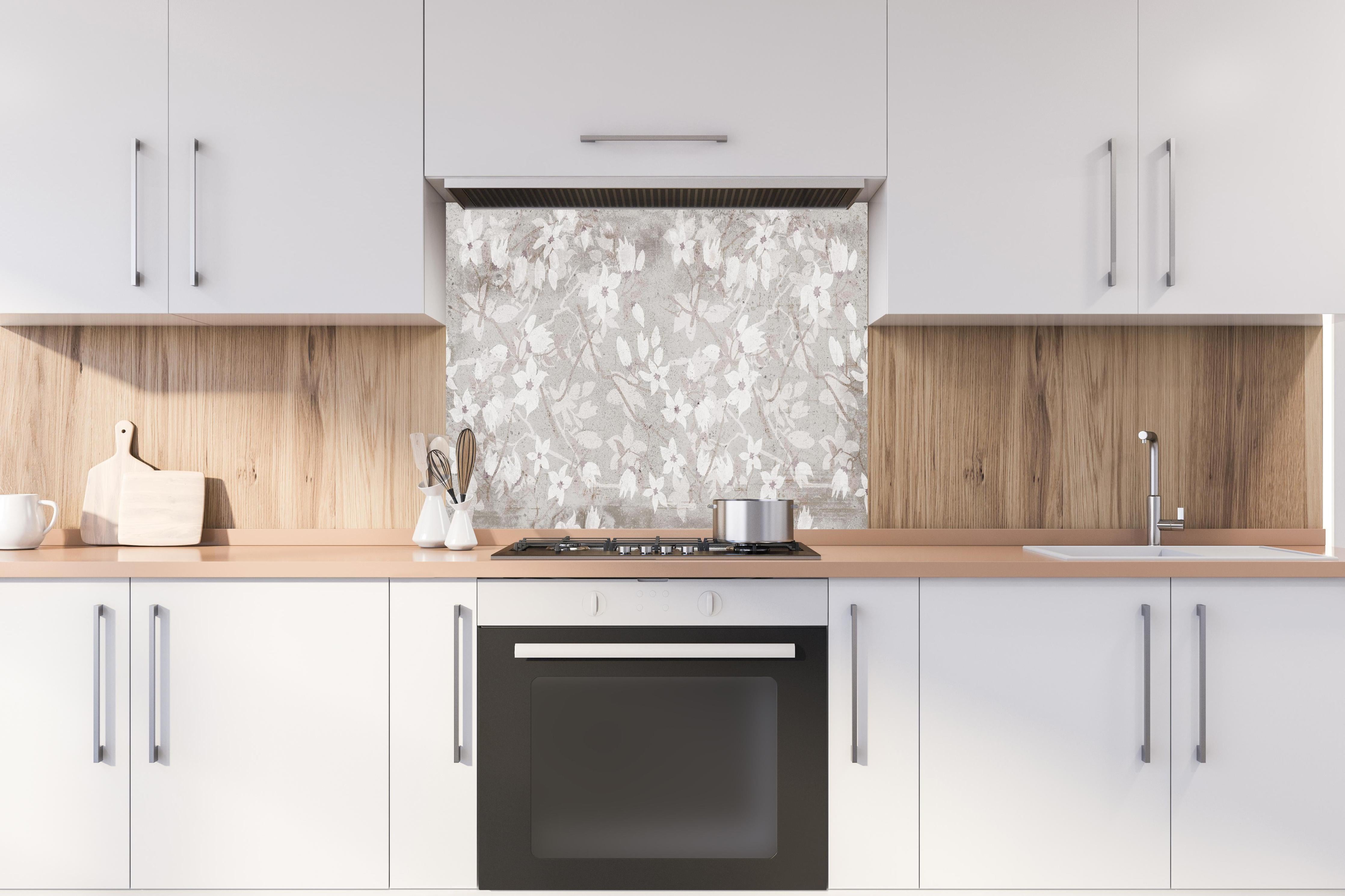 Spritzschutz - Weiße Blumen auf altem grauem Hintergrund hinter einem Cerankochfeld zwischen Holz-Kochutensilien