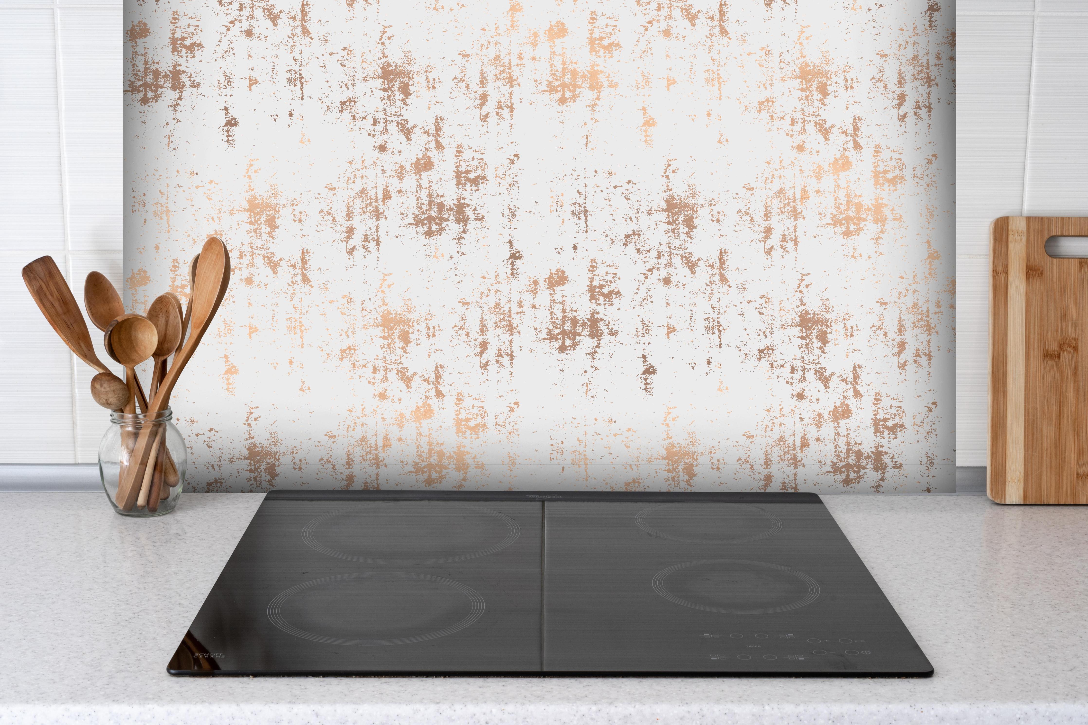 Spritzschutz - Weiße Textur mit goldenen Akzenten hinter einem Cerankochfeld zwischen Holz-Kochutensilien