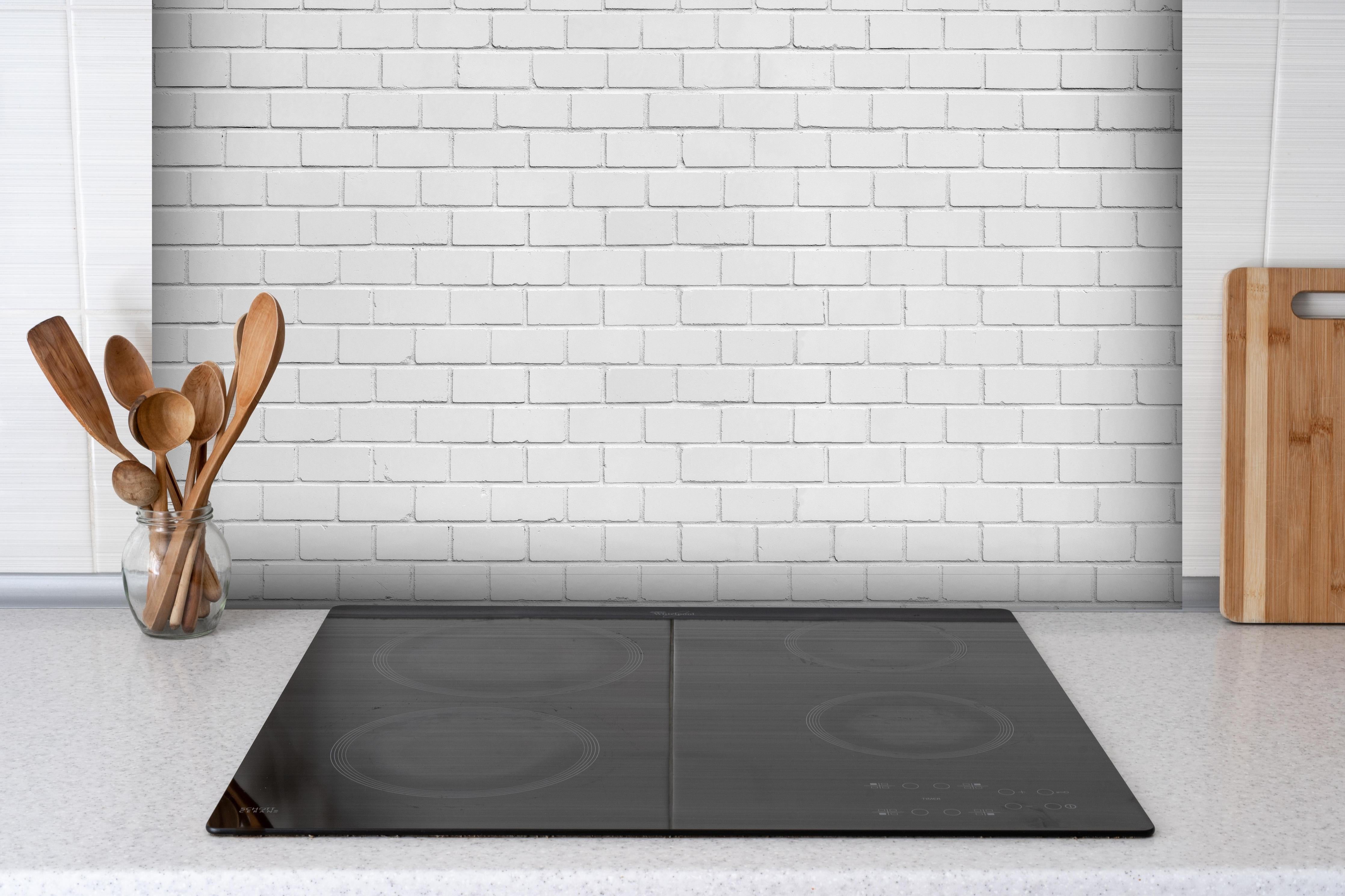 Spritzschutz - Weiße Ziegelwand - Zement hinter einem Cerankochfeld zwischen Holz-Kochutensilien