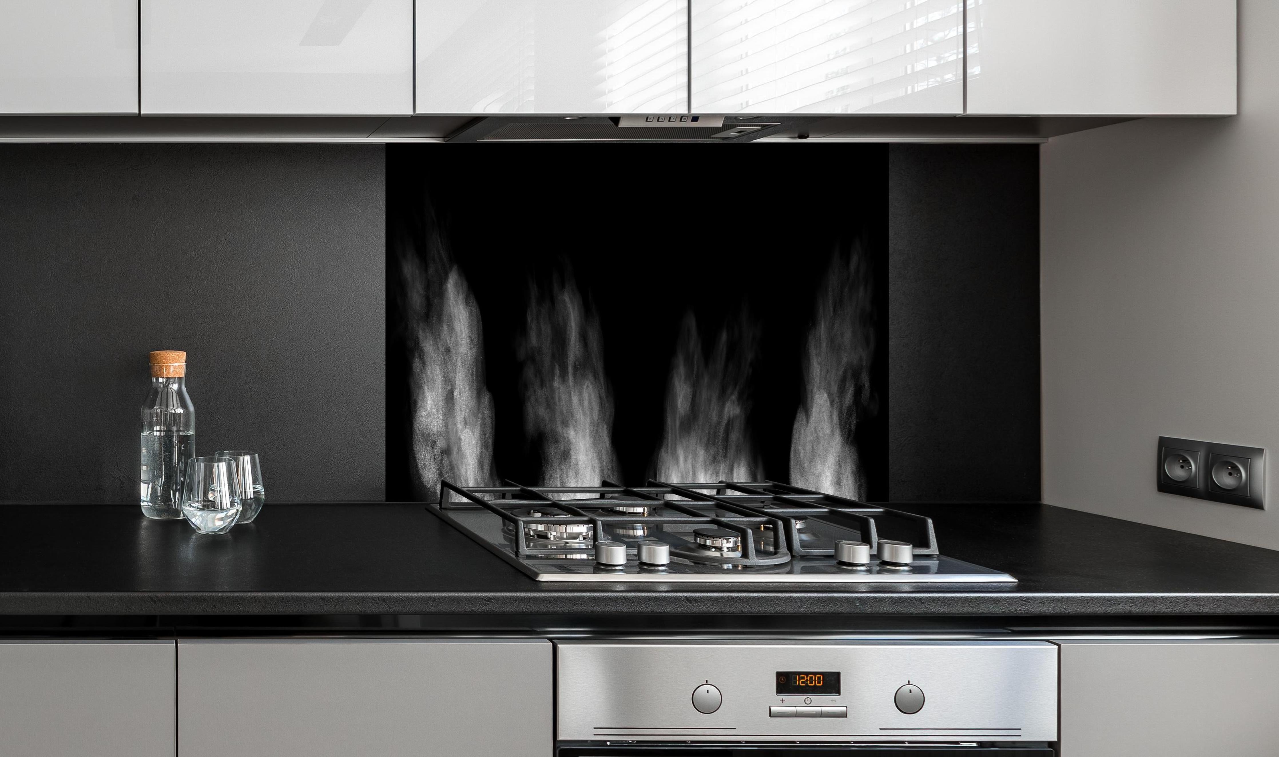 Spritzschutz - Weißer Dampf hinter einem Cerankochfeld zwischen Holz-Kochutensilien