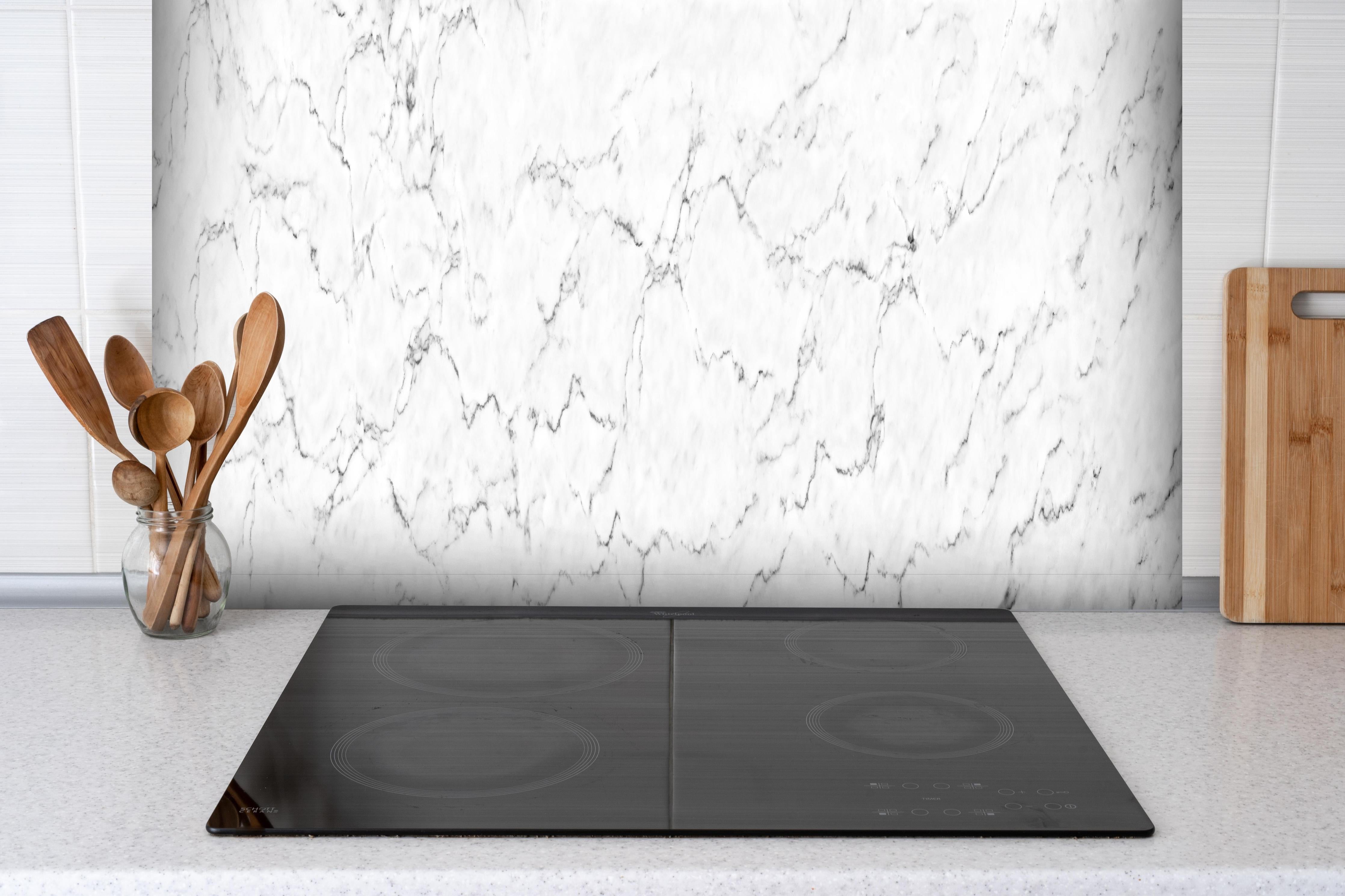 Spritzschutz - Weißer Marmor hinter einem Cerankochfeld zwischen Holz-Kochutensilien