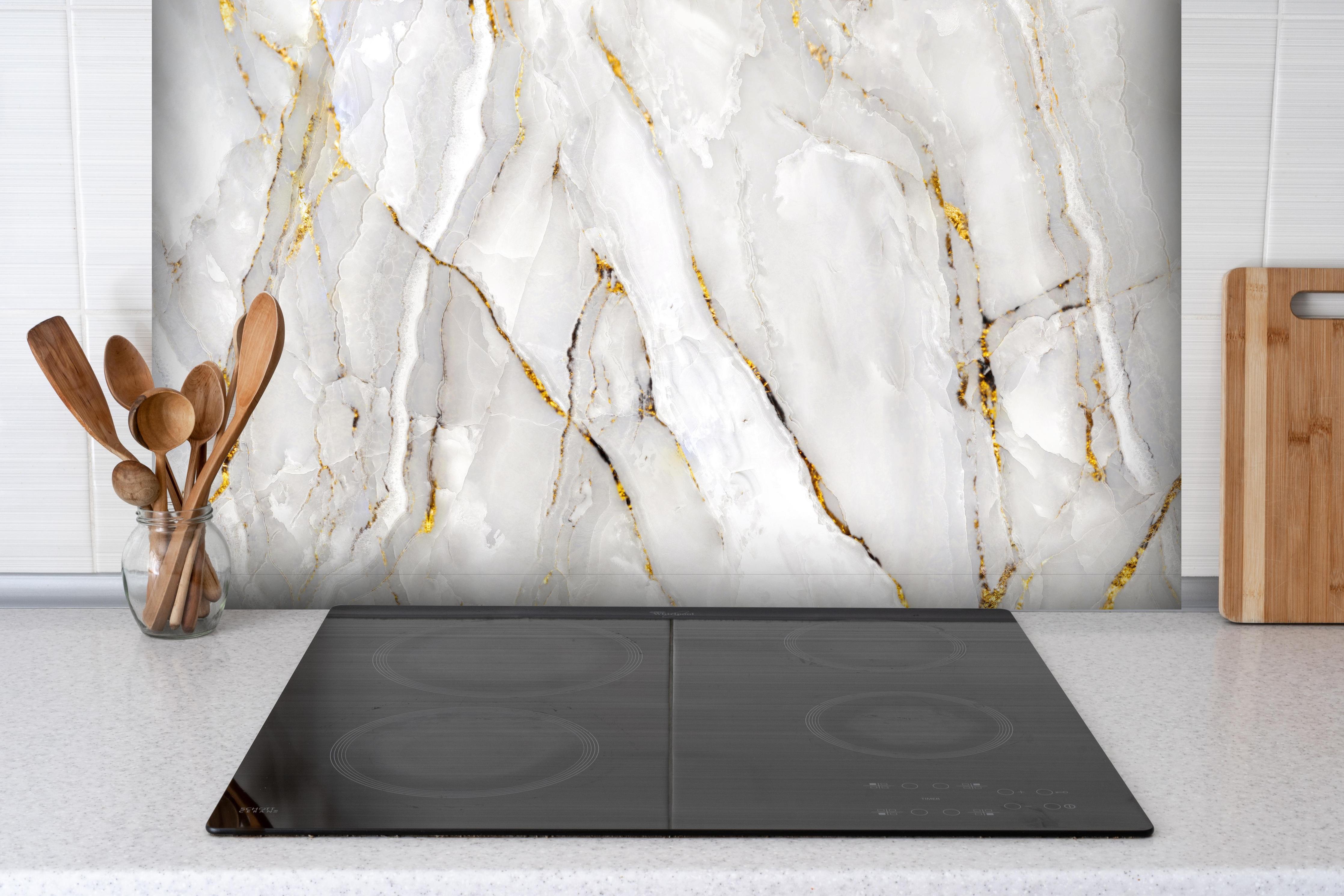 Spritzschutz - Weißer Statuario-Marmor mit goldene Adern hinter einem Cerankochfeld zwischen Holz-Kochutensilien