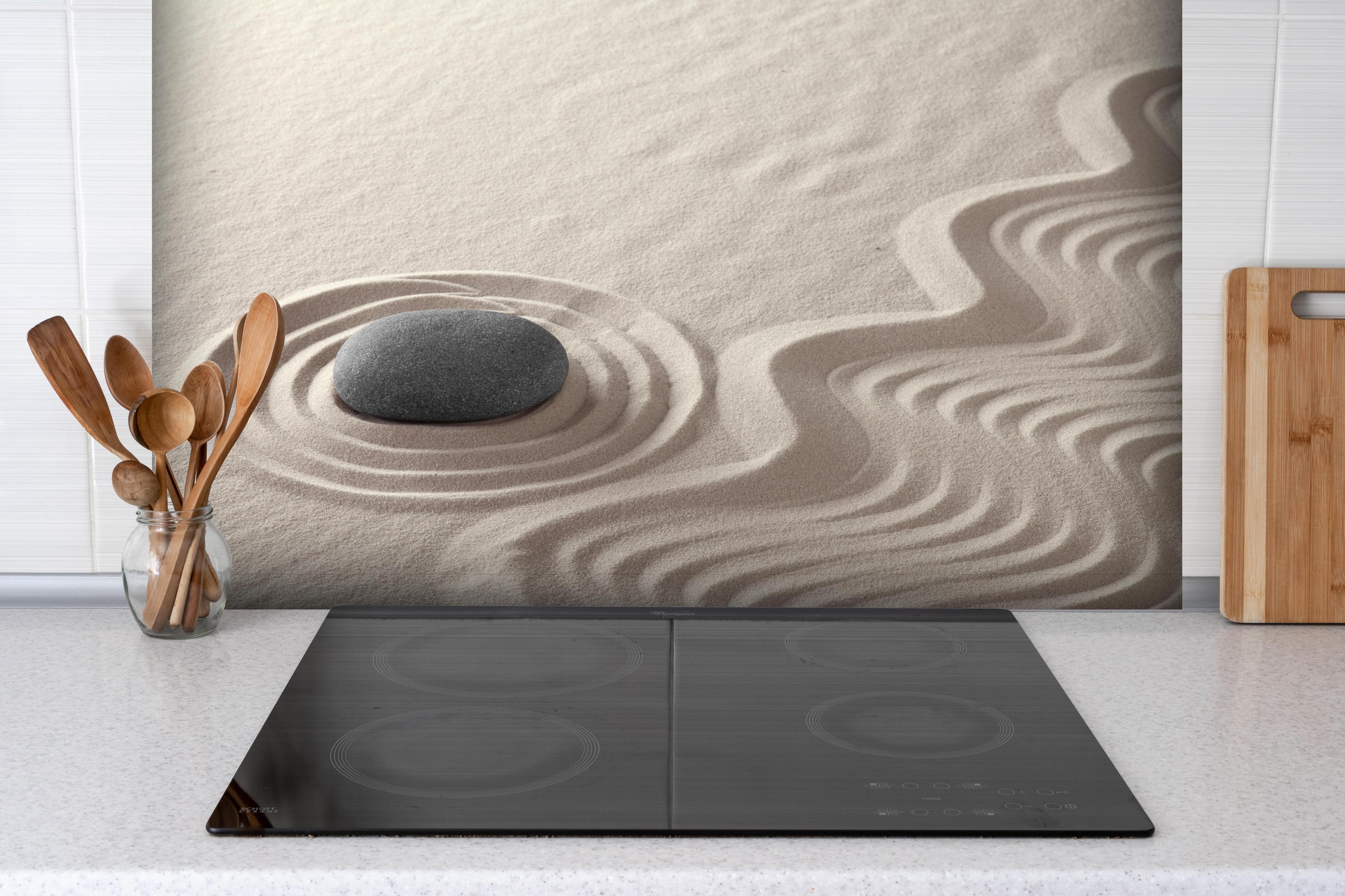 Spritzschutz - Weißer Zen-Garten mit grauem Stein hinter einem Cerankochfeld zwischen Holz-Kochutensilien