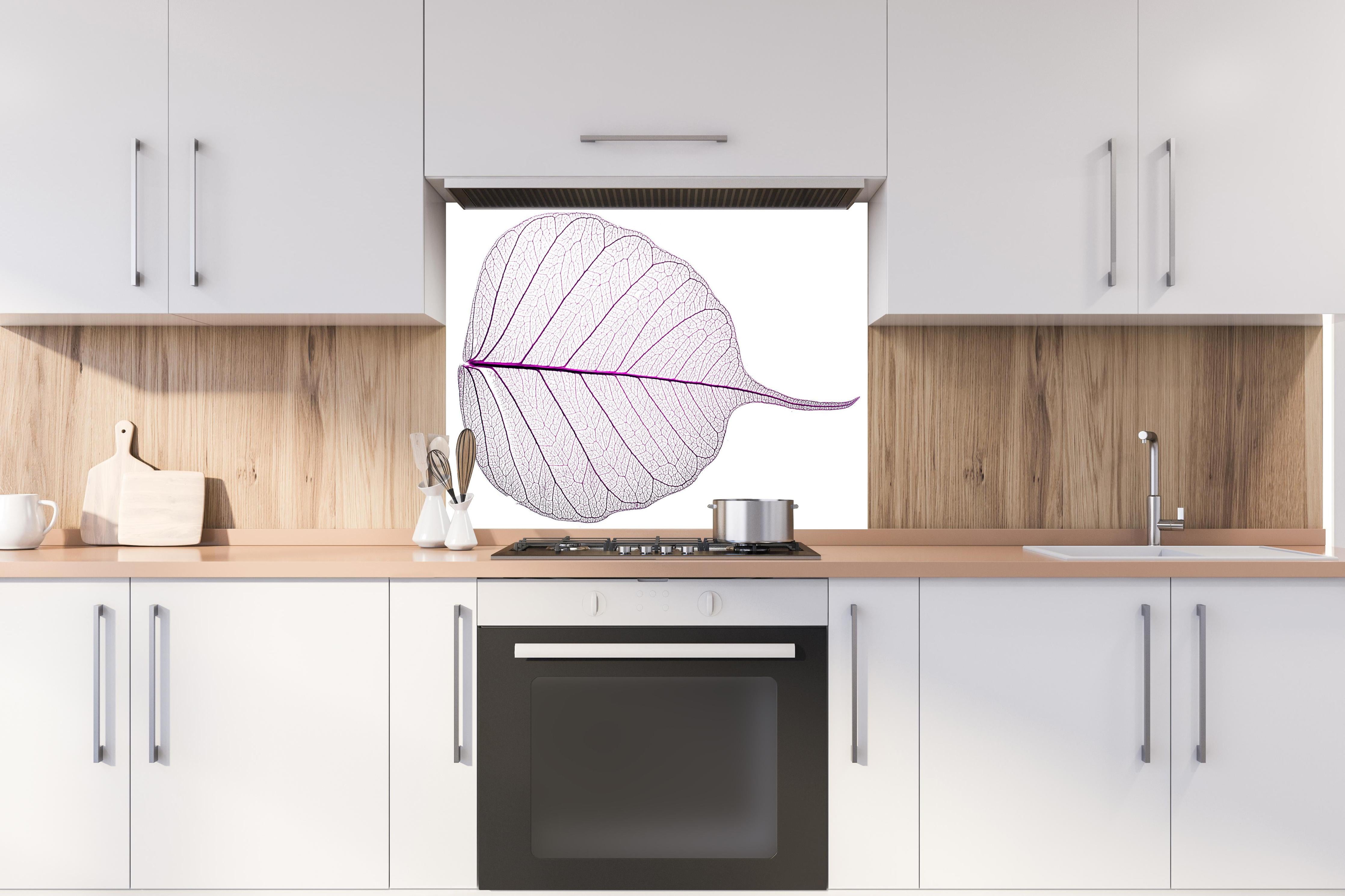 Spritzschutz - Weißes Blatt Skelett mit lila Akzent hinter einem Cerankochfeld zwischen Holz-Kochutensilien
