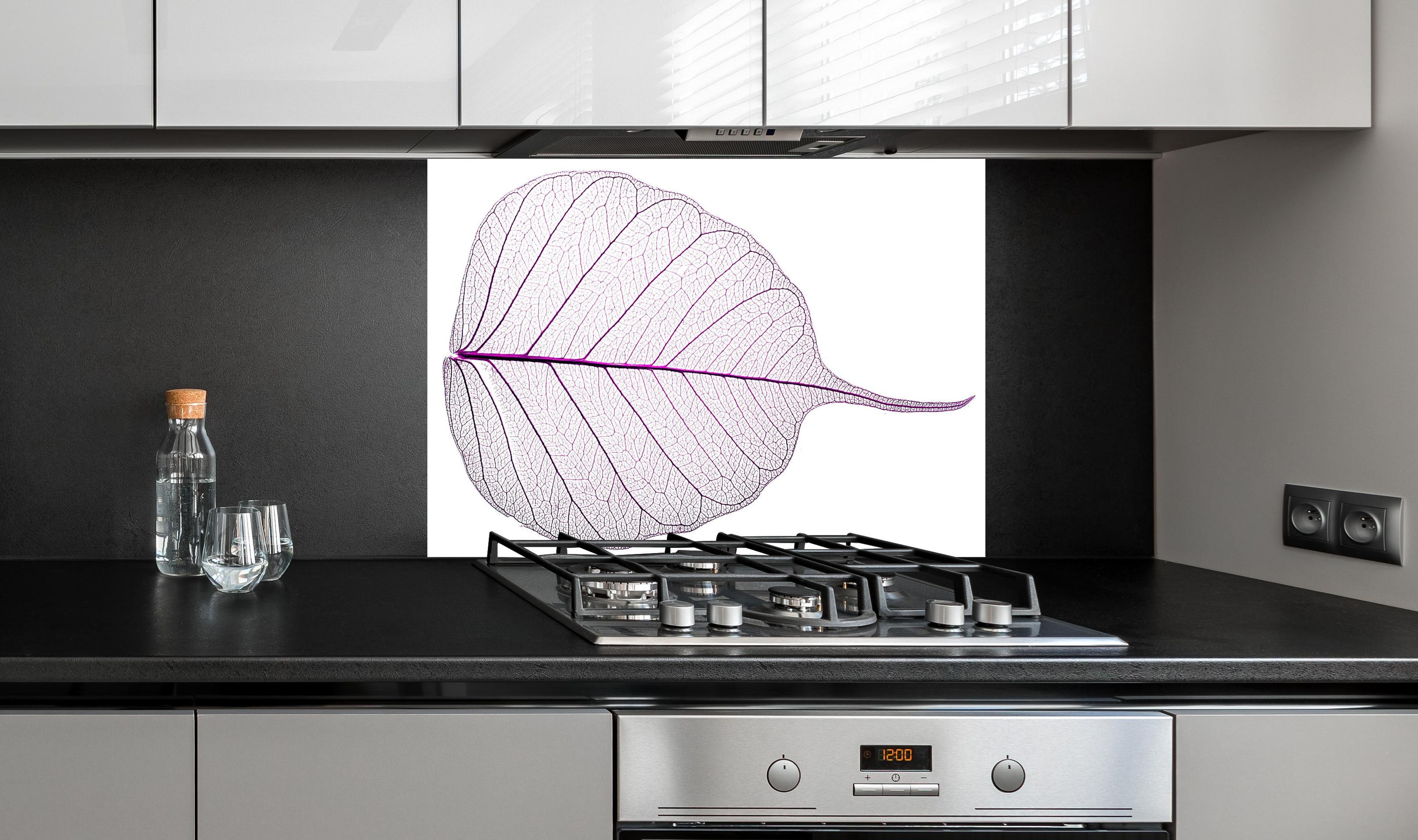 Spritzschutz - Weißes Blatt Skelett mit lila Akzent hinter einem Cerankochfeld zwischen Holz-Kochutensilien