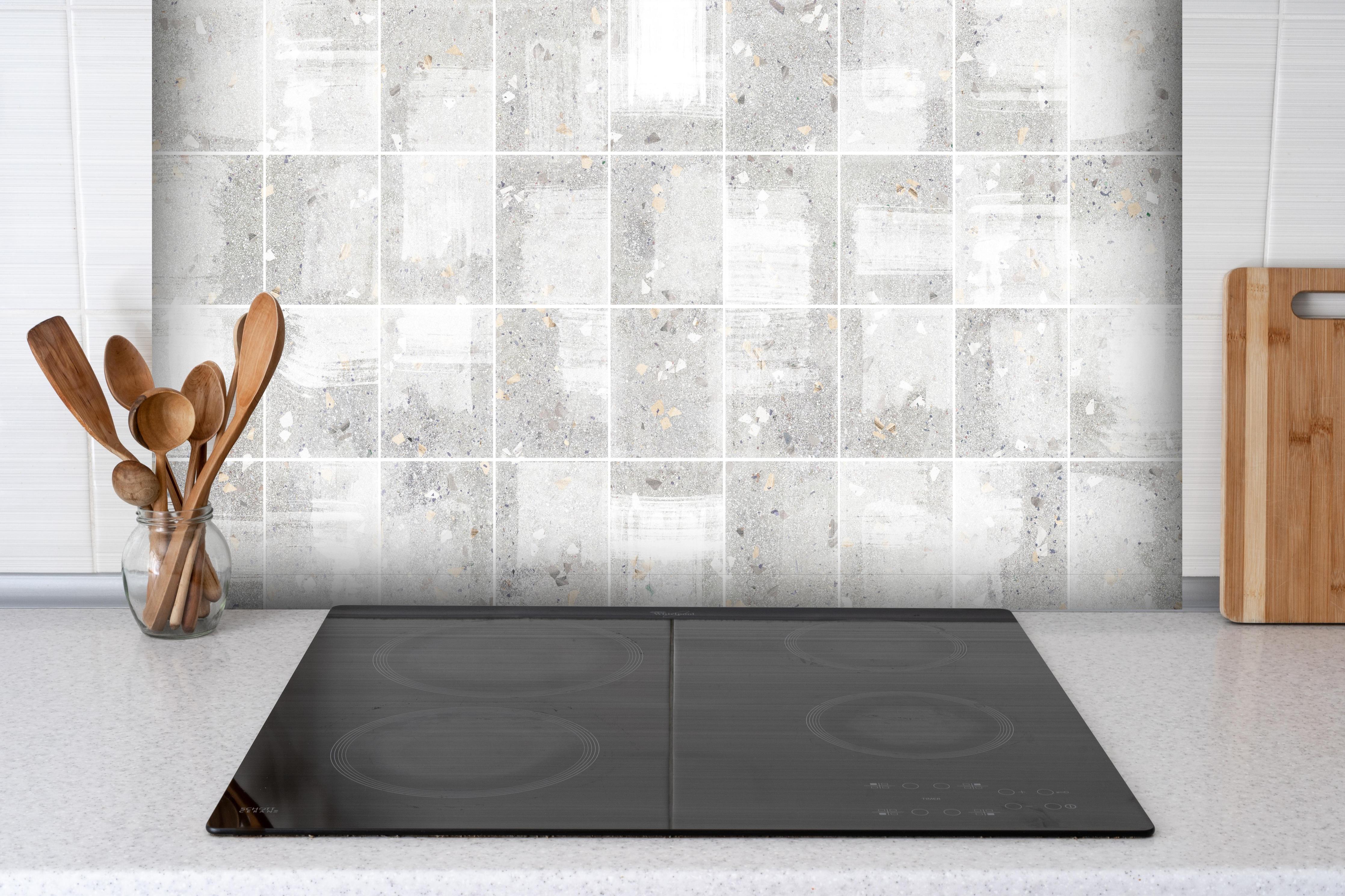 Spritzschutz - Weißes Fliesenmuster - Terrazzo Struktur hinter einem Cerankochfeld zwischen Holz-Kochutensilien