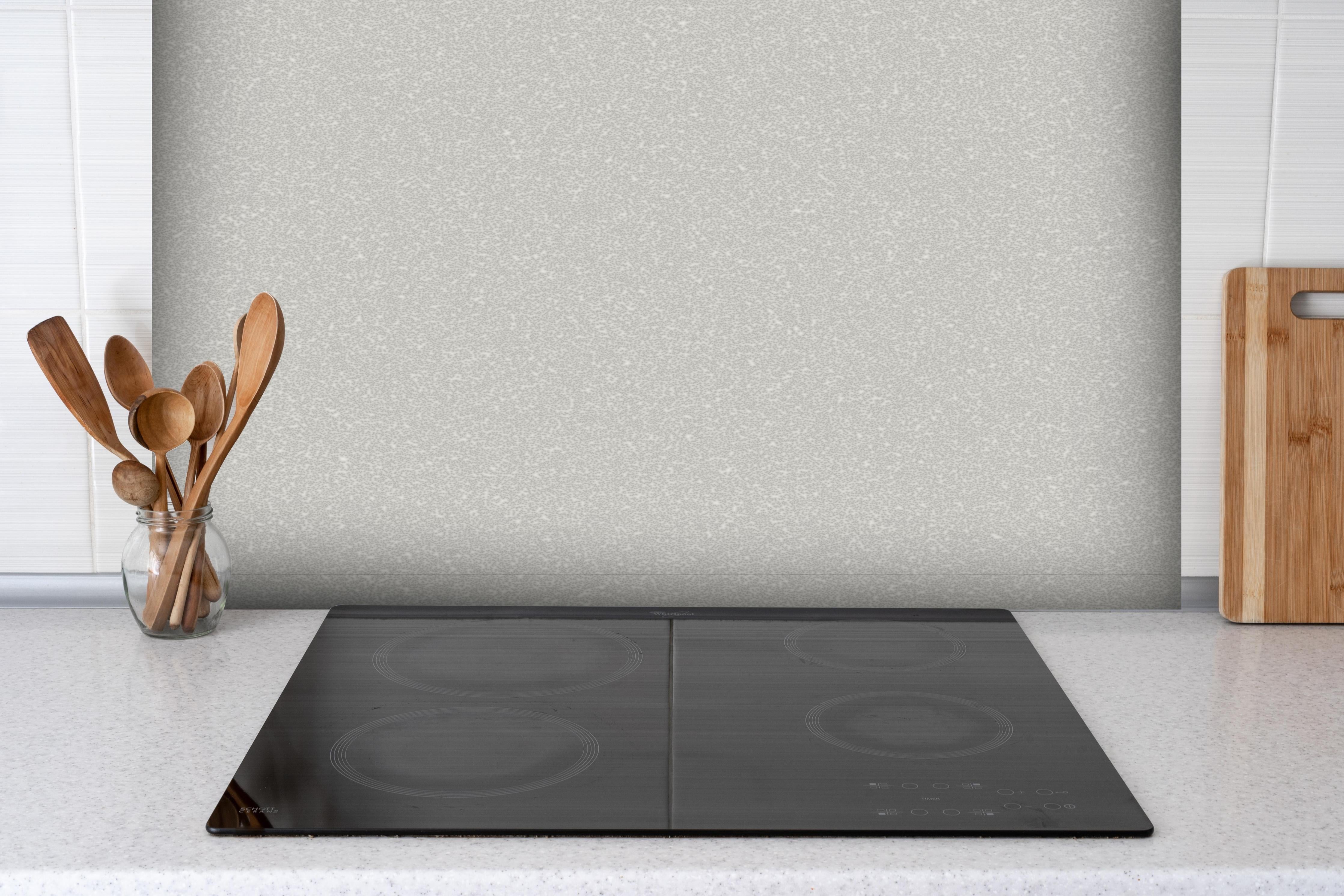 Spritzschutz - Weißes Wandmuster hinter einem Cerankochfeld zwischen Holz-Kochutensilien