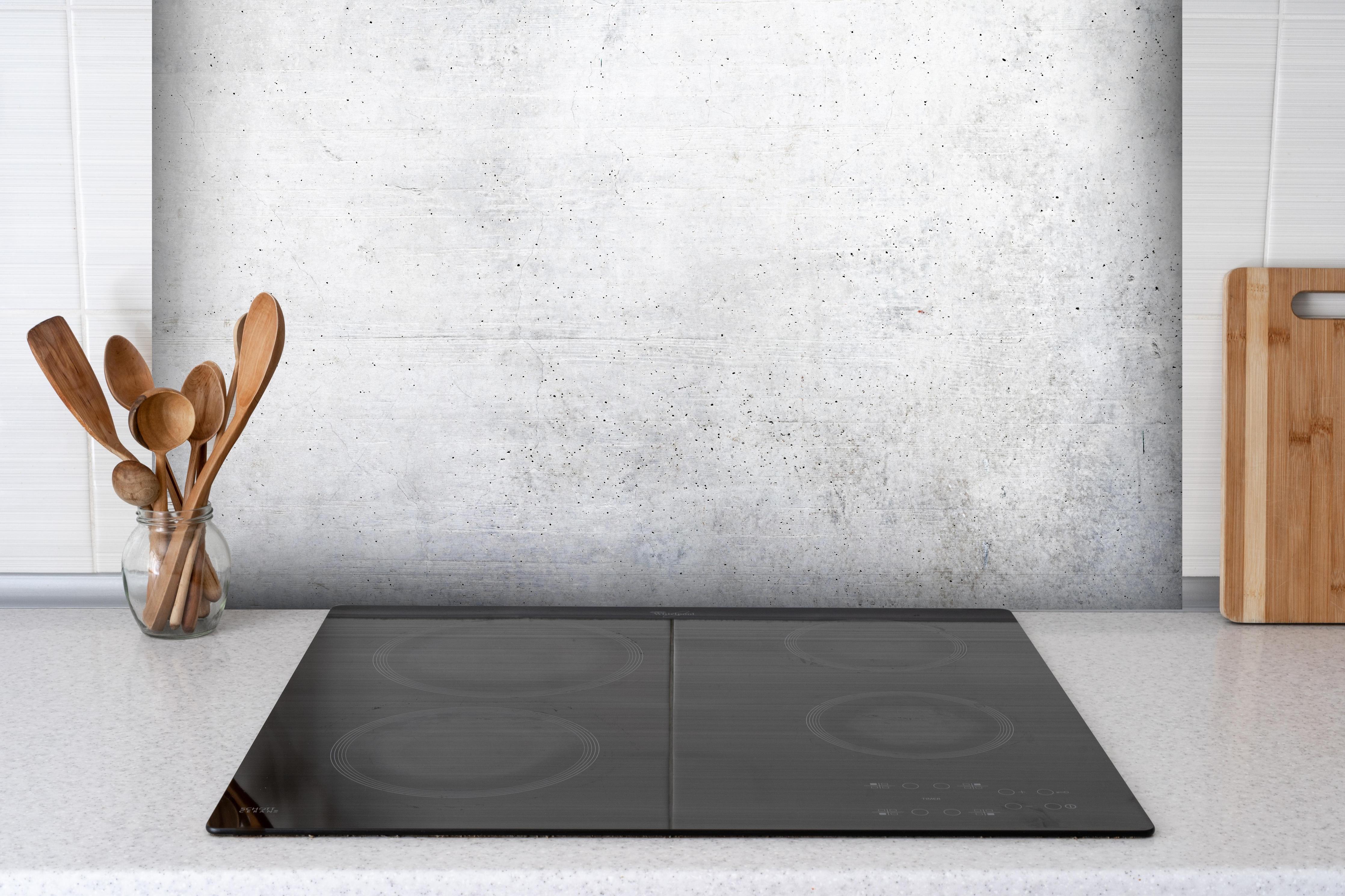Spritzschutz - Weißes Zement Design hinter einem Cerankochfeld zwischen Holz-Kochutensilien