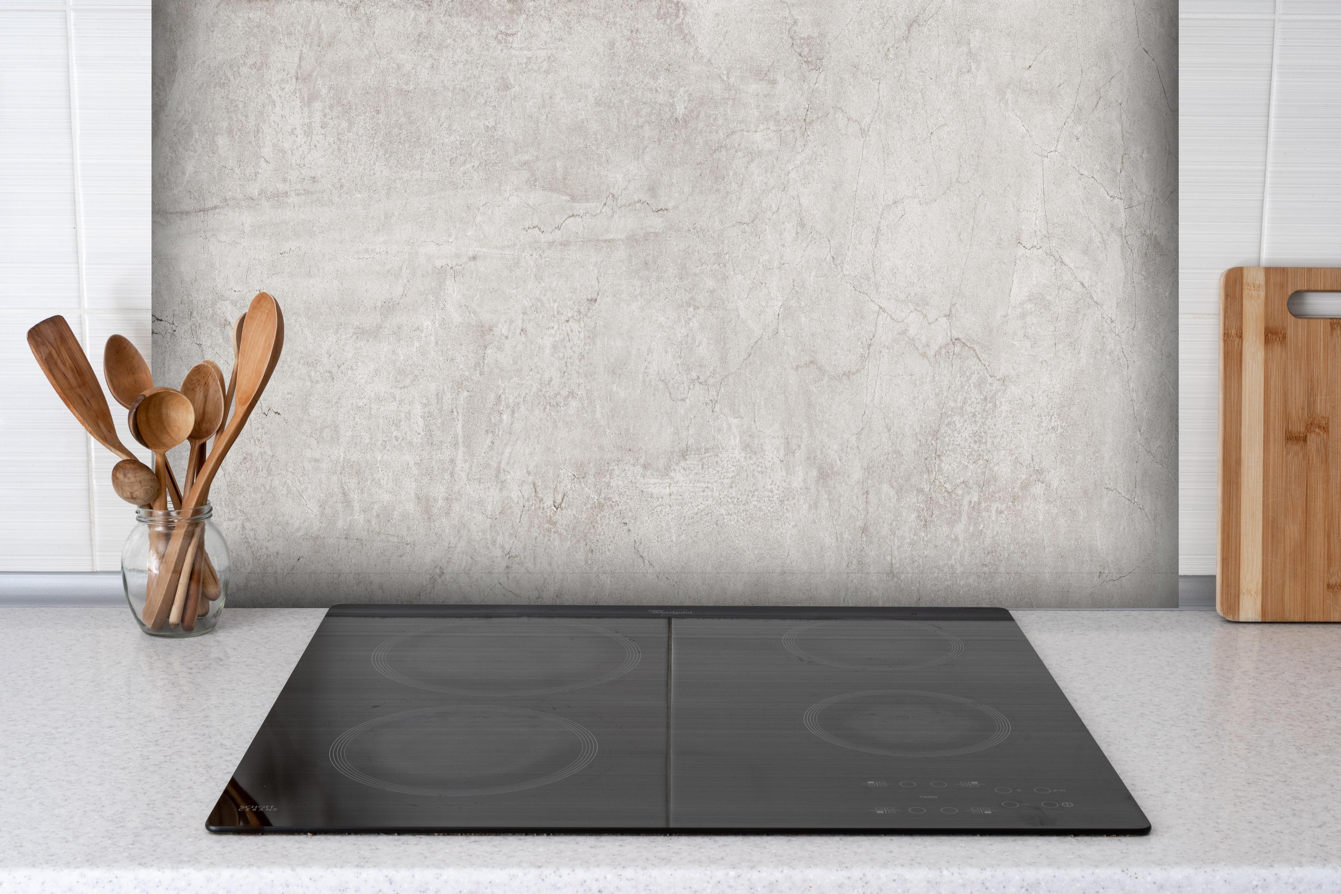 Spritzschutz - Weißliche Zement Textur hinter einem Cerankochfeld zwischen Holz-Kochutensilien