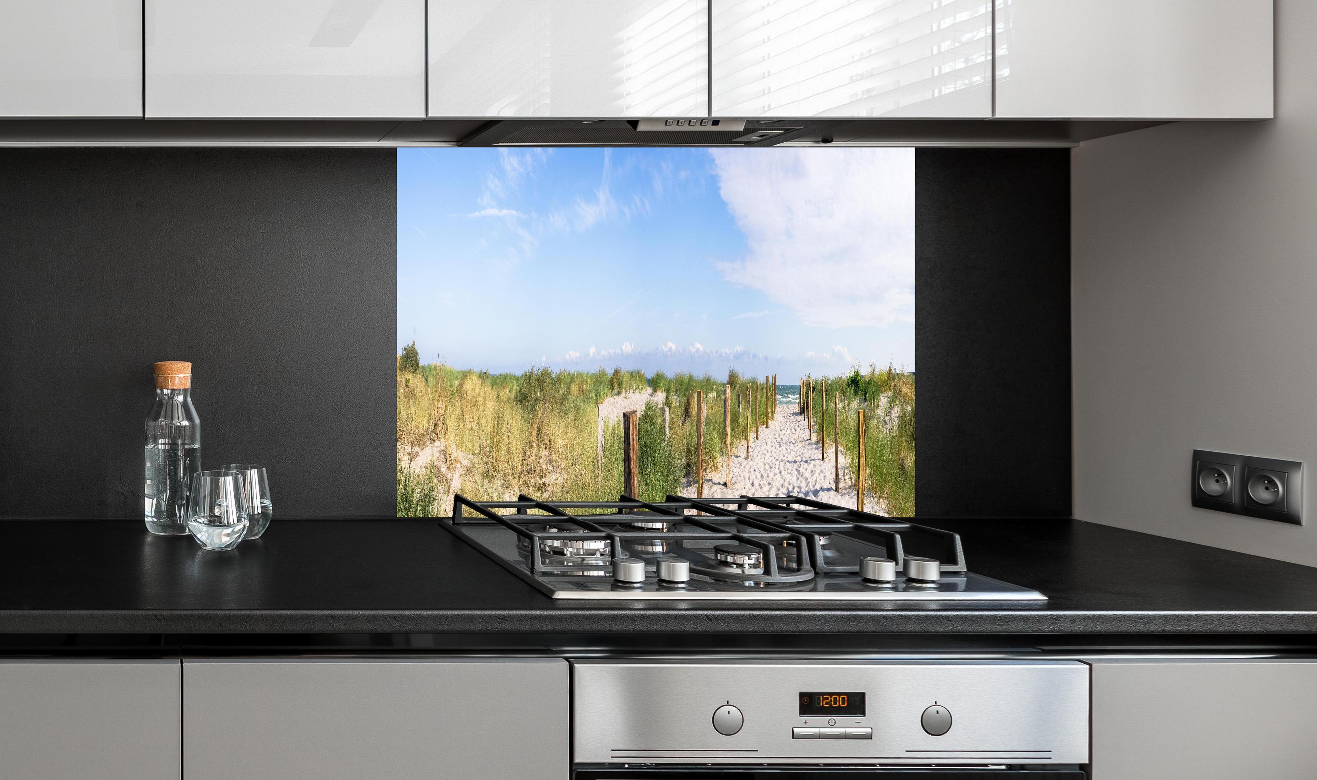 Spritzschutz - Weites Dünenpanorama Strandblick hinter einem Cerankochfeld zwischen Holz-Kochutensilien