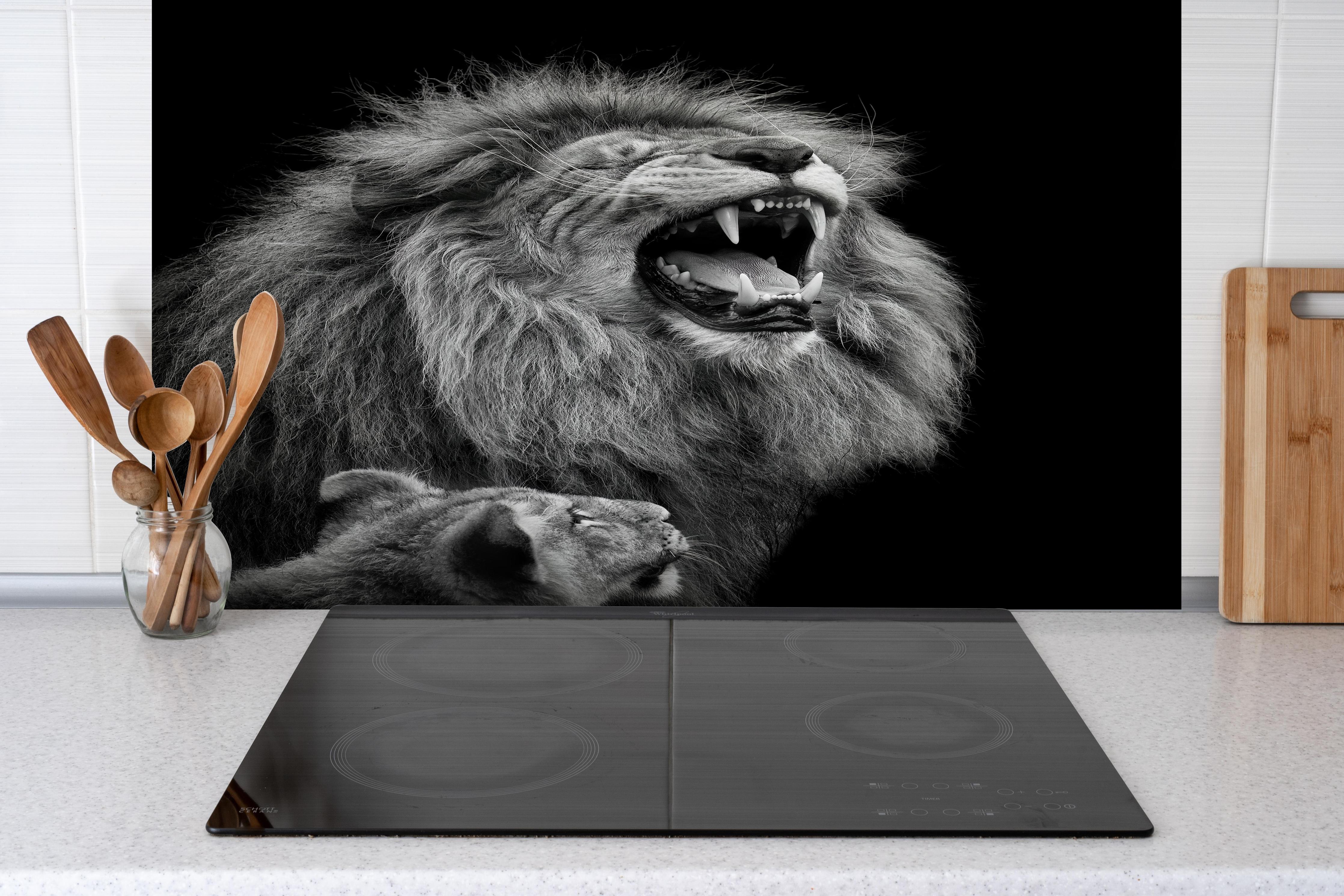 Spritzschutz - Wildtiere auf schwarzem Hintergrund hinter einem Cerankochfeld zwischen Holz-Kochutensilien