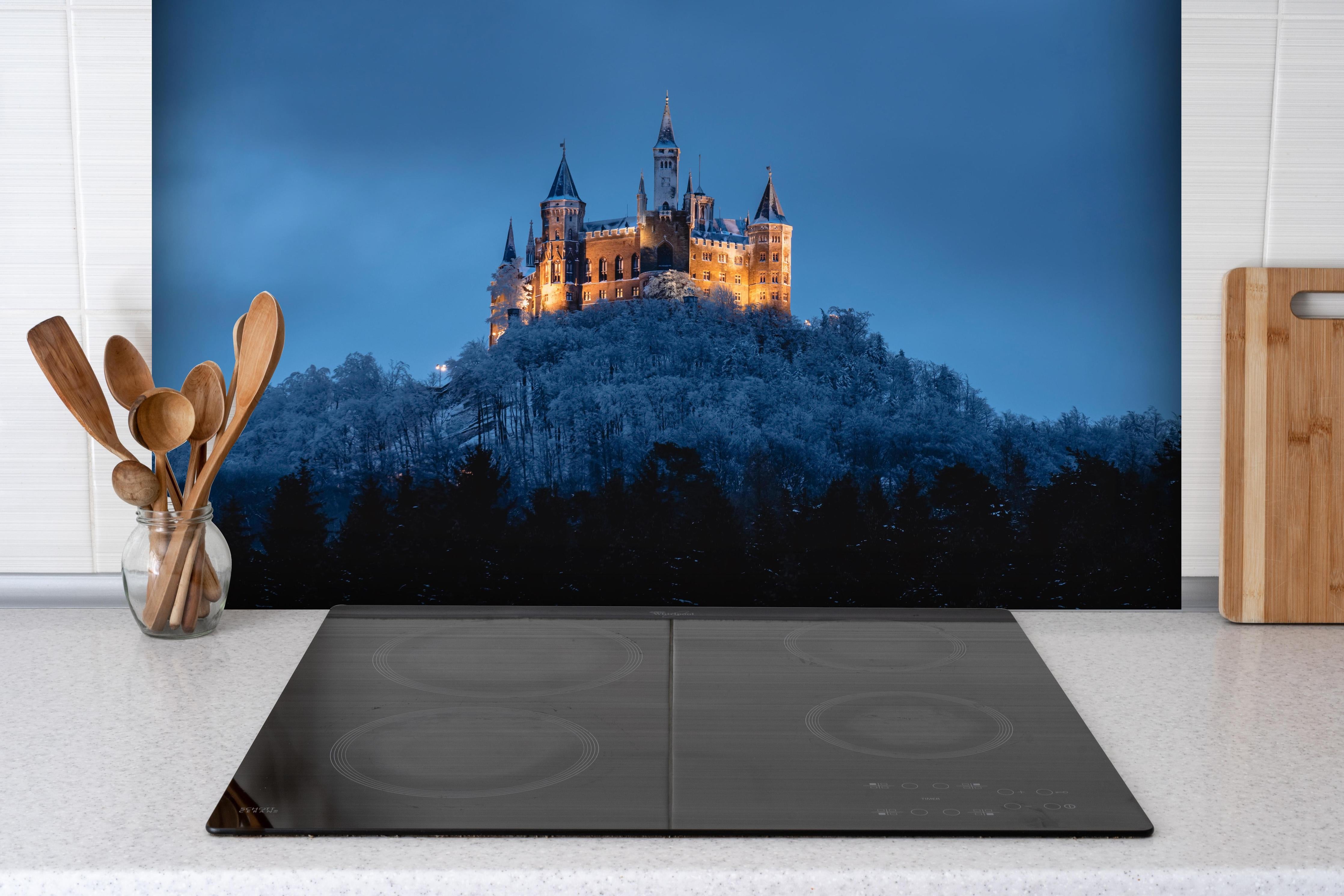 Spritzschutz - Winterliche Atmosphäre - Burg von Hohenzollern hinter einem Cerankochfeld zwischen Holz-Kochutensilien