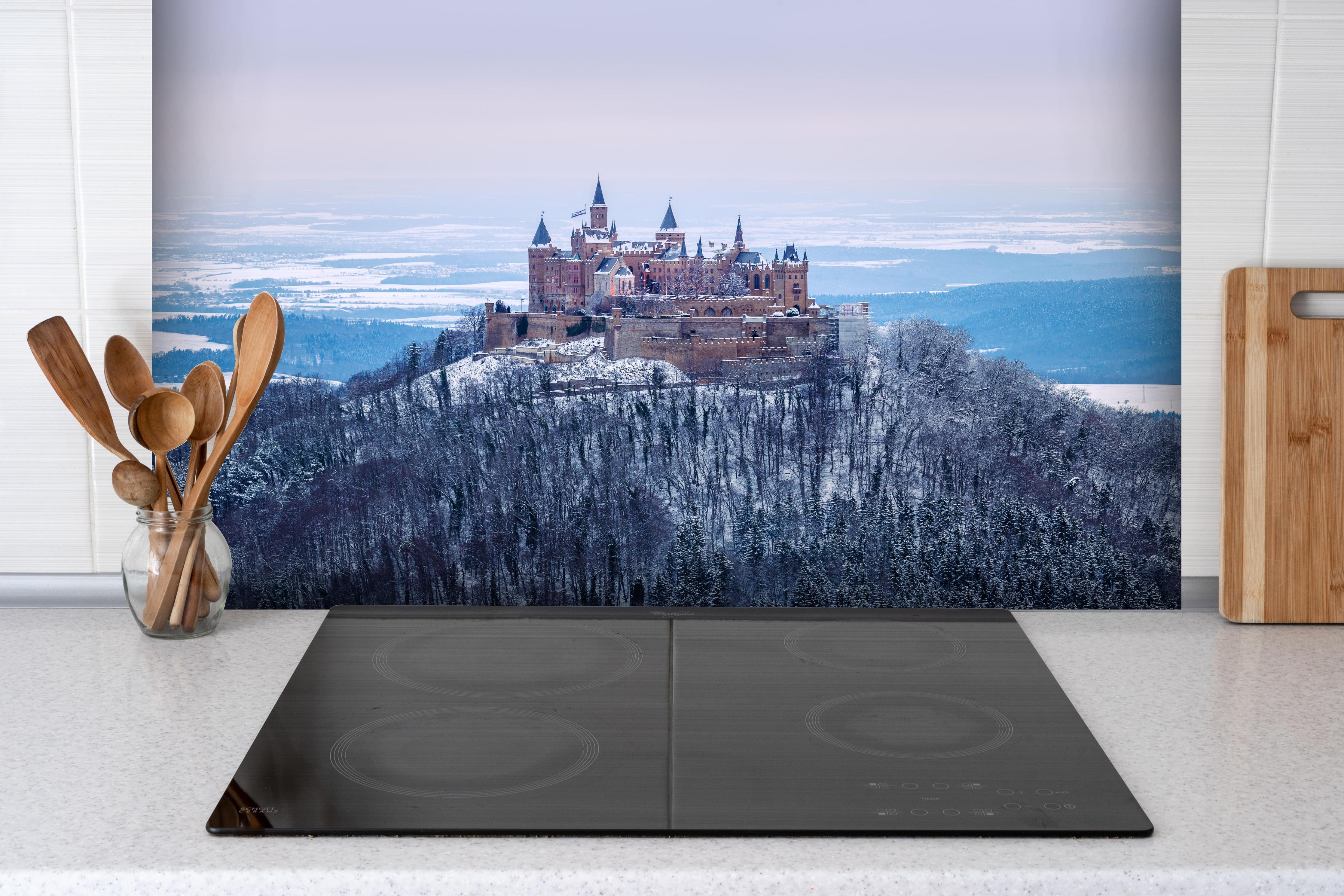 Spritzschutz - Winterliche Burg von Hohenzollern hinter einem Cerankochfeld zwischen Holz-Kochutensilien