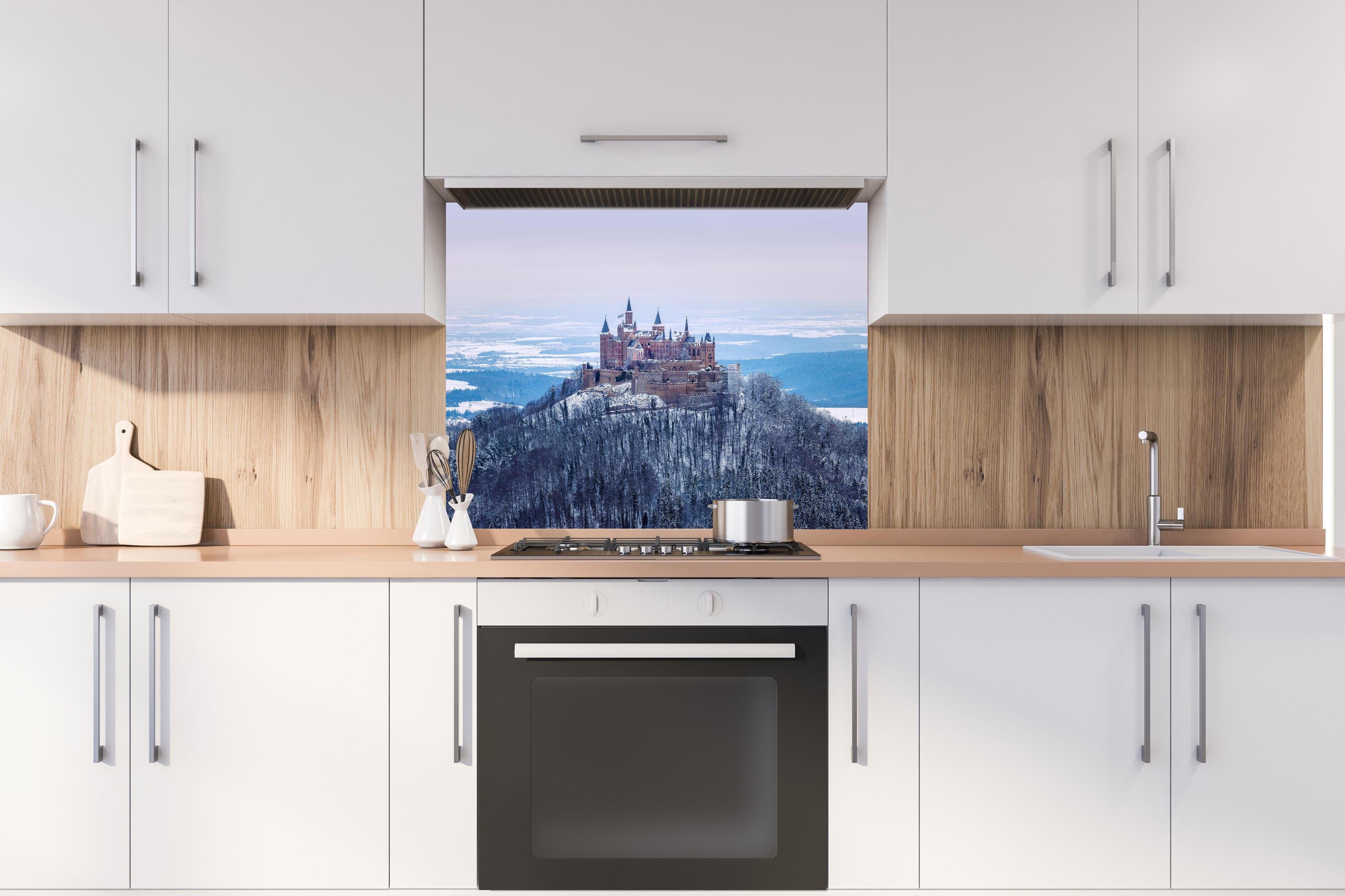 Spritzschutz - Winterliche Burg von Hohenzollern hinter einem Cerankochfeld zwischen Holz-Kochutensilien