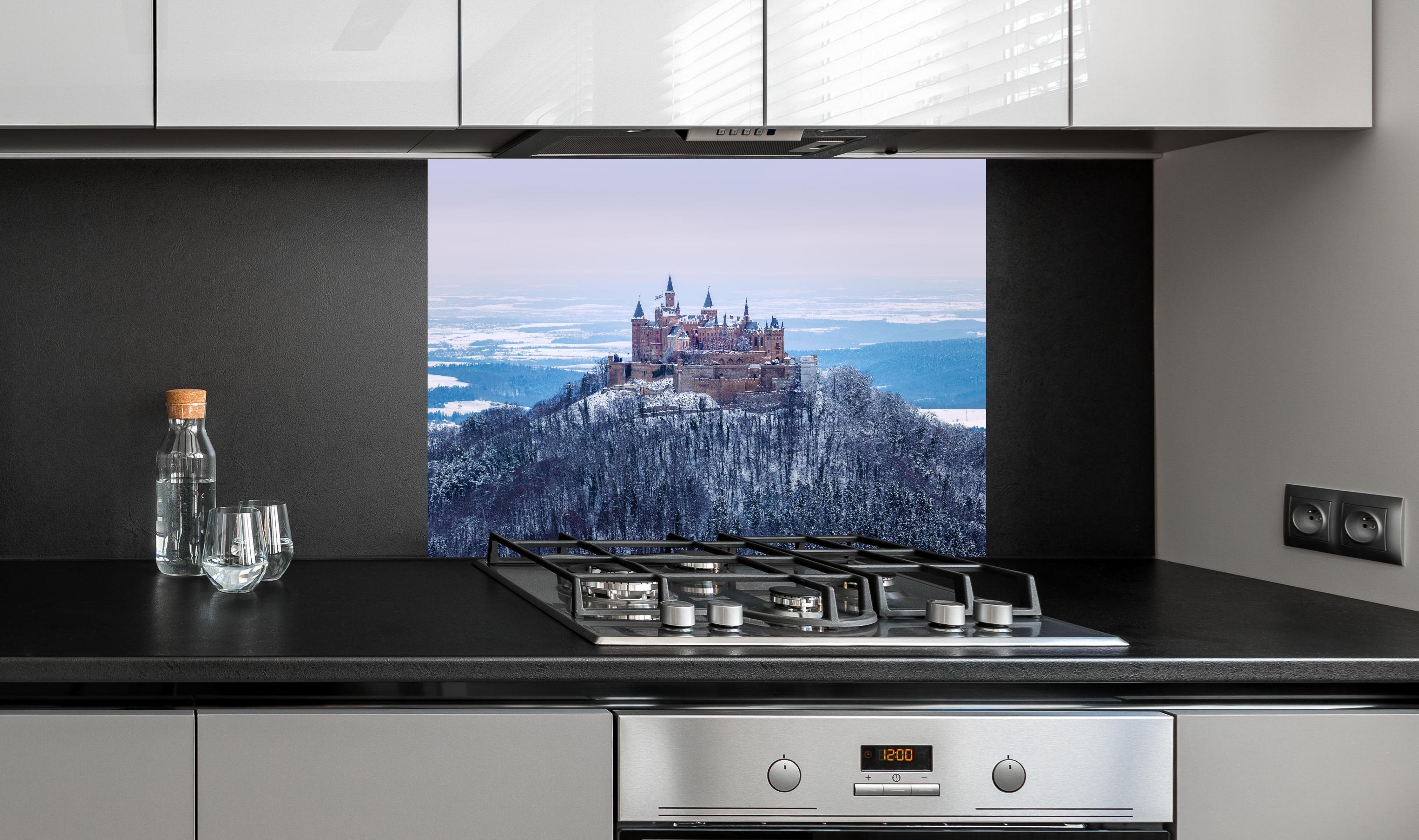 Spritzschutz - Winterliche Burg von Hohenzollern hinter einem Cerankochfeld zwischen Holz-Kochutensilien